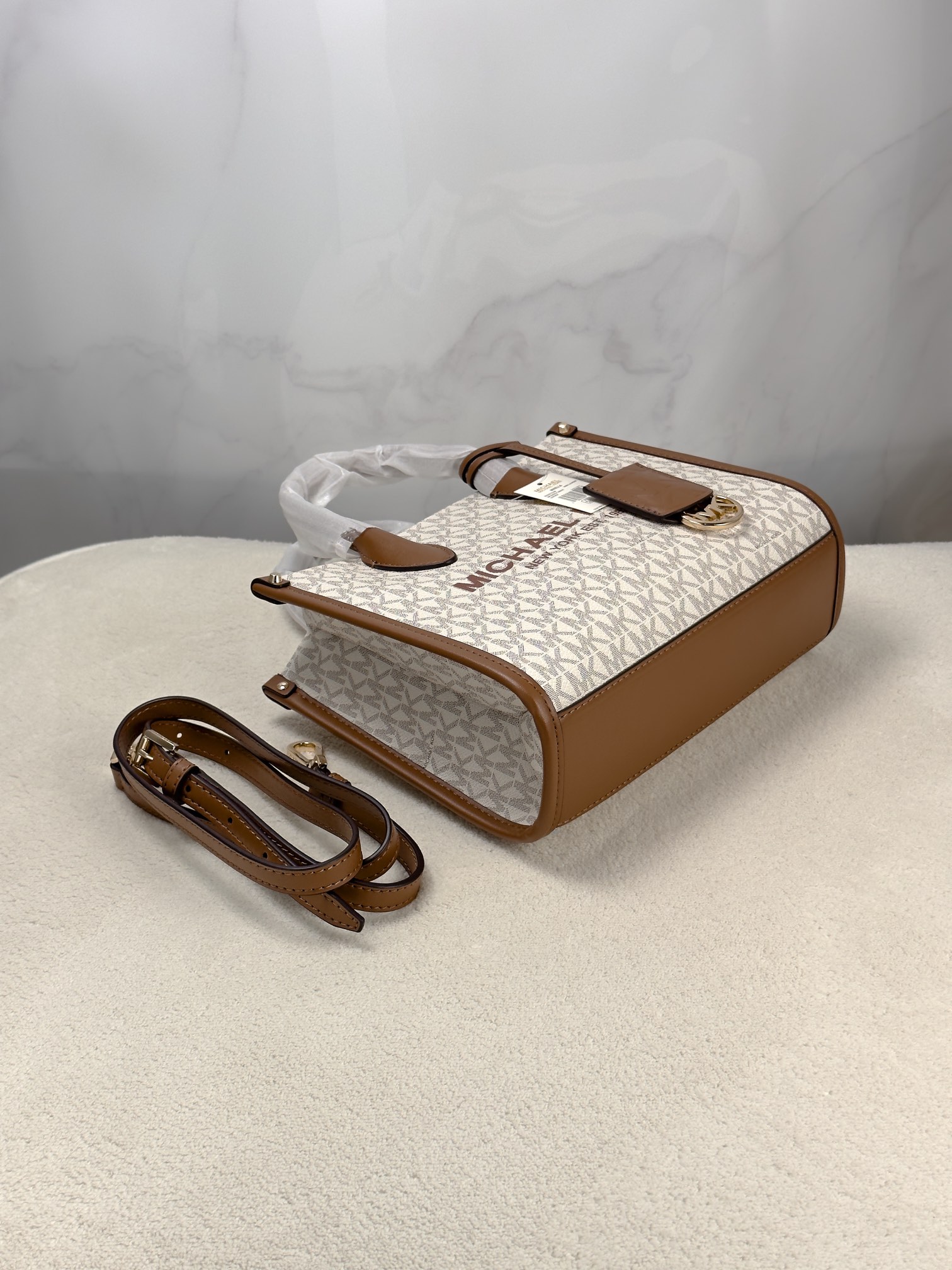 Michael Kors 印花打造包身，上缀 Michael Kors 字母印花装饰，皮革