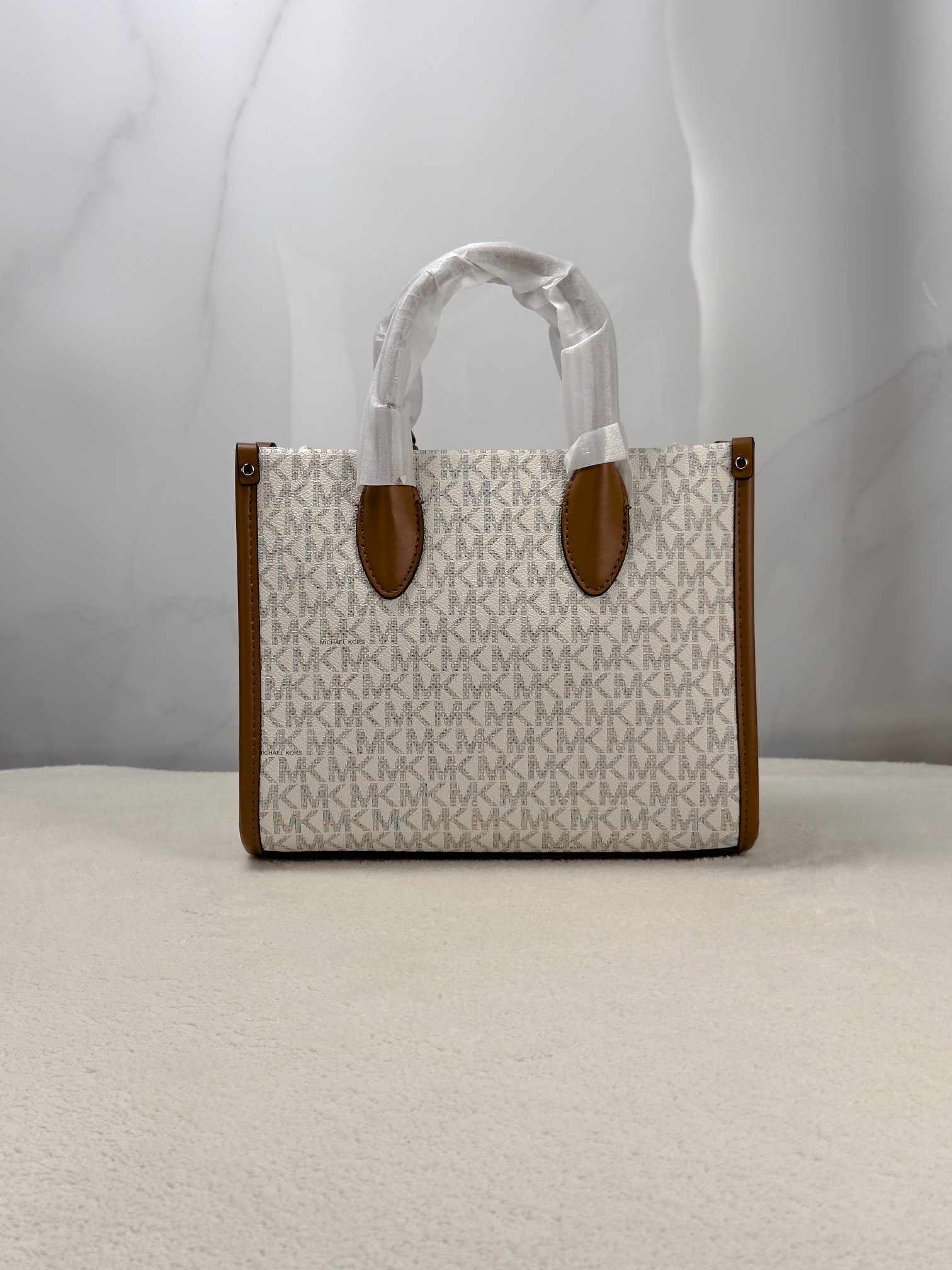Michael Kors 印花打造包身，上缀 Michael Kors 字母印花装饰，皮革