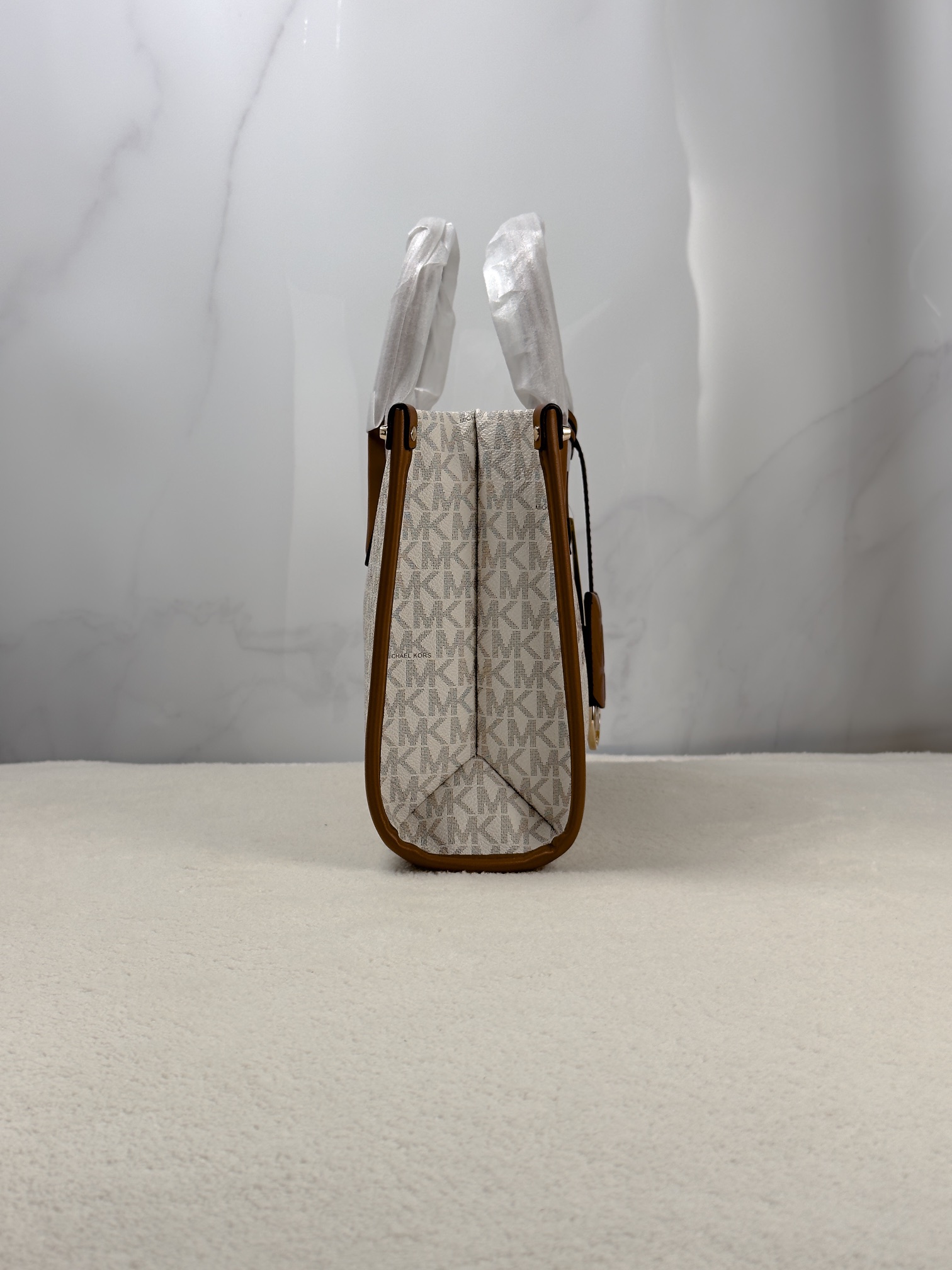 Michael Kors 印花打造包身，上缀 Michael Kors 字母印花装饰，皮革