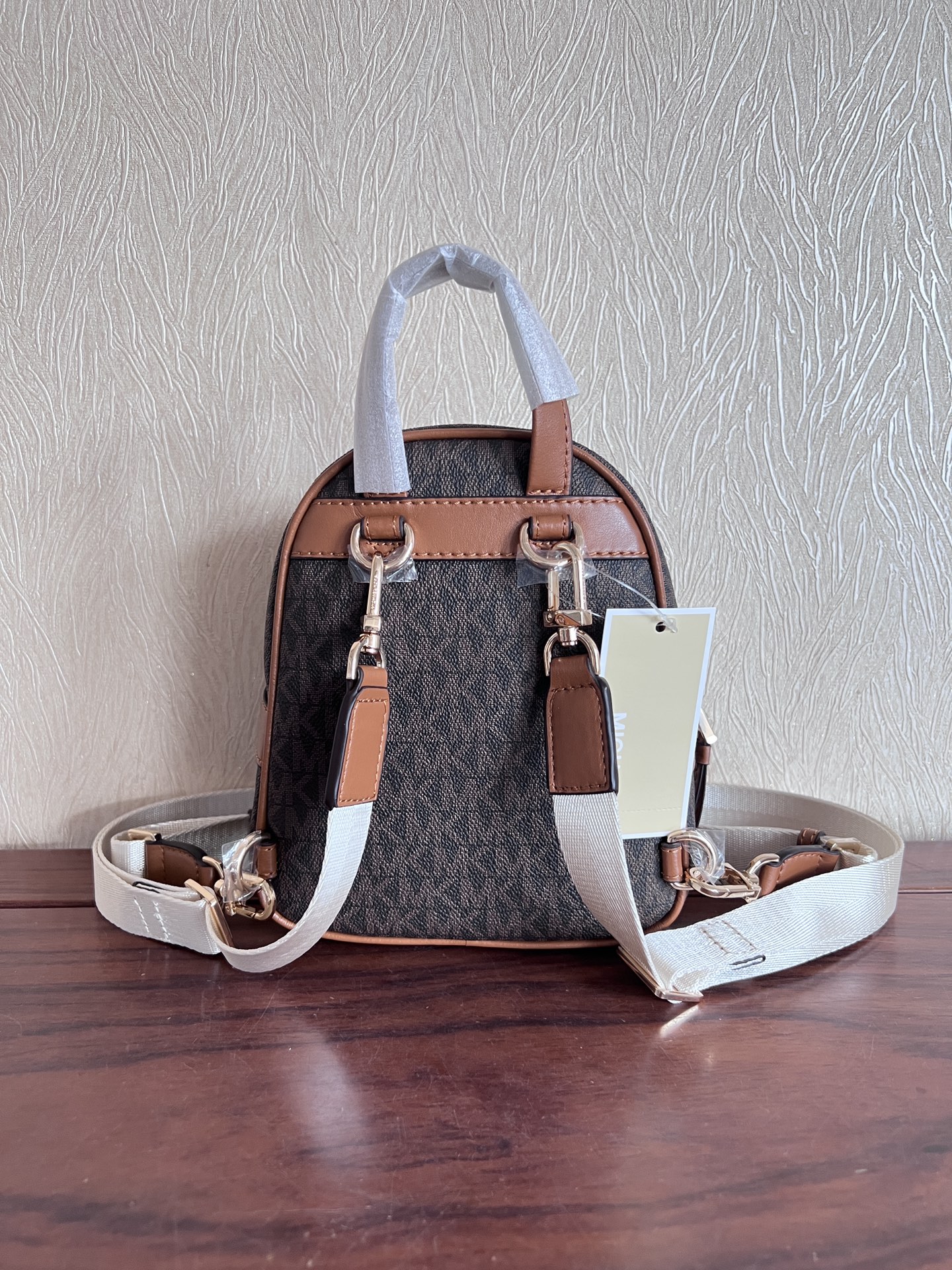 Michael Kors ～此款Elliot 超小号老花双肩包 采用香草白色品牌标志性 Logo印花材质打造小巧包身