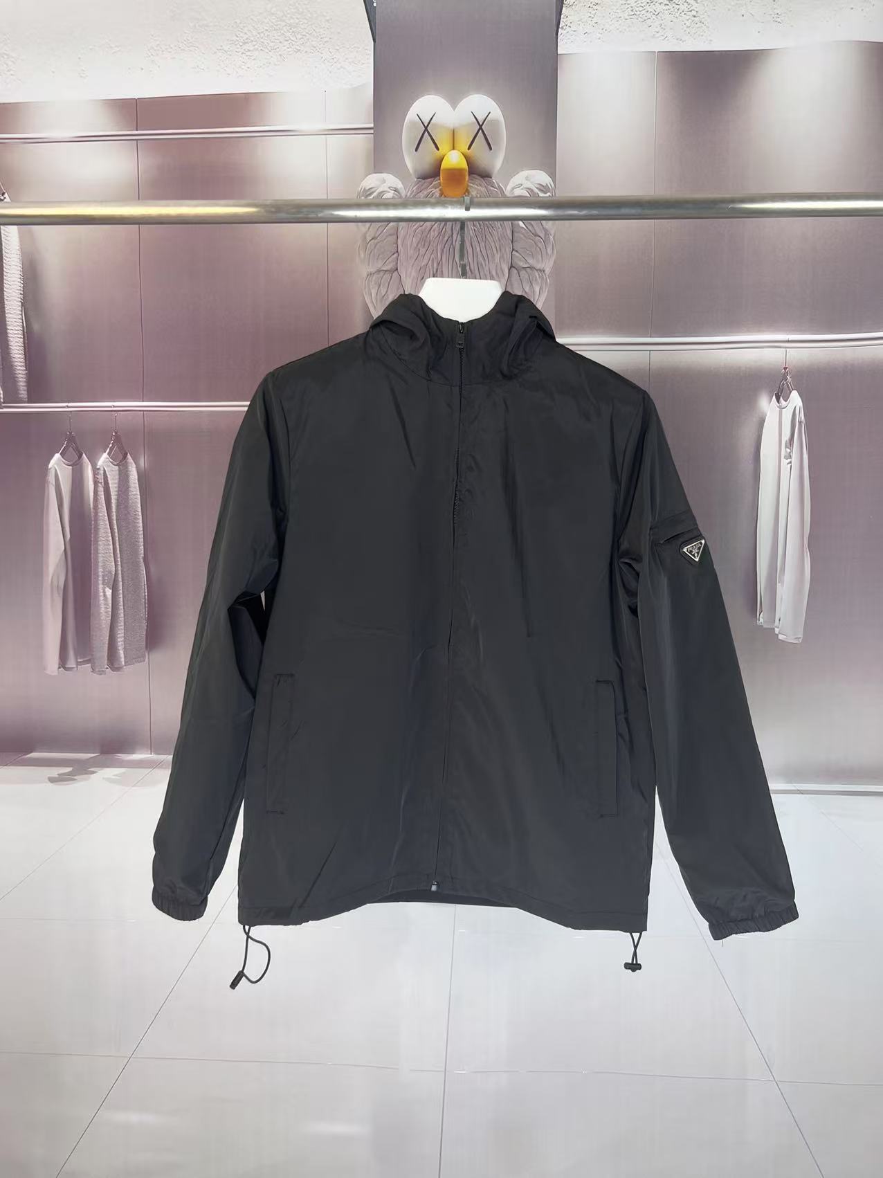 P190✨✨
 Prada 普拉达 2025秋冬新款 连帽风衣夹克外套 薄款冲锋衣 袖子口袋三角标刺绣 官网同步   原版定做五金拉链 走线工整 上身效果完美 男士休闲外套
颜色：黑色
尺码：M-3XL