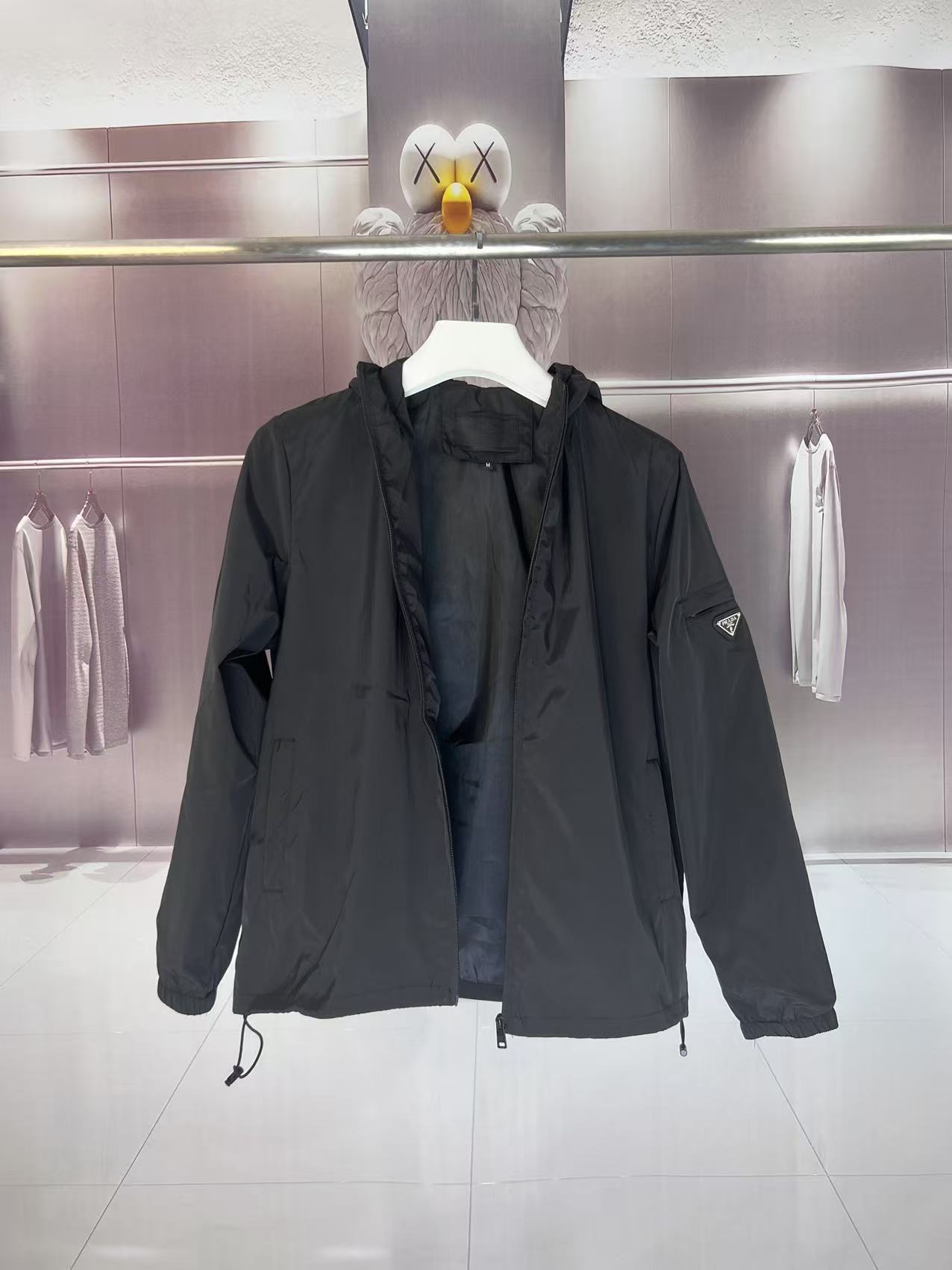 P190✨✨
 Prada 普拉达 2025秋冬新款 连帽风衣夹克外套 薄款冲锋衣 袖子口袋三角标刺绣 官网同步   原版定做五金拉链 走线工整 上身效果完美 男士休闲外套
颜色：黑色
尺码：M-3XL