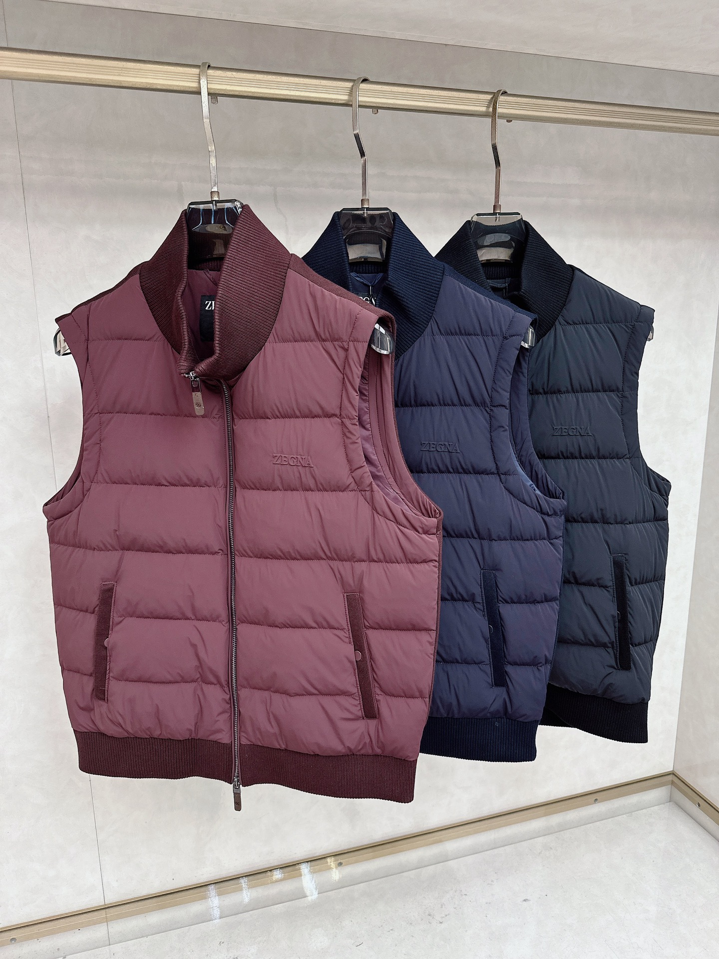 NO:596926,Zegna's new autumn and winter down vest, with light beige as the main color, shows the elegance of a modern gentleman through its stand-up collar design and precise tailoring. This vest is filled with high-quality down and has a regular quilted plaid on the surface, which effectively fixes the thermal material and adds a three-dimensional texture. The front is equipped with a smooth zipper opening and closing system, and the pockets on both sides are decorated with white piping details, which cleverly echoes the overall simple style. The collar and hem are made of elastic rib knitting to ensure a good fit.  It is comfortable and not easy to deform. The brand logo is embellished on the left chest, low-key showing the luxury gene. The fabric is made of polyamide, which has both light texture and durability. The lining contains 91 polyamide and 9 elastic fibers, which provide moderate extensibility. As a layering tool in autumn and winter, it can be paired with shirts or sweaters to create a multi-layered look. It perfectly balances practical functions and Italian aesthetics, and is suitable for business, leisure and daily social occasions. 48-56,,zegna,shirts,down  jacket,alexander wang19860909Zegna杰尼亚、秋冬新品羽绒马甲,以浅米色为主色调,通过立领设计与精准剪裁展现现代绅士的优雅风度.这款马甲采用高品质羽绒填充,表面呈现规整的绗缝格纹,既有效固定保暖材料又增添立体质感.前襟配备顺滑拉链开合系统,两侧口袋饰以白色滚边细节,与整体简约风格形成巧妙呼应.衣领及下摆采用弹性罗纹针织工艺,确保贴合舒适且不易变形.左胸处点缀品牌标识,低调彰显奢华基因.面料选用聚酰胺材质,兼具轻盈质感与耐用特性,里料含91聚酰胺与9弹性纤维,提供适度延展性.作为秋冬叠穿利器,可搭配衬衫或针织衫打造多层次造型,完美平衡实用功能与意式美学,适用于商务休闲与日常社交等多种场合.48-56,,zegna,shirts,down jacket,alexander wang,Men's clothing