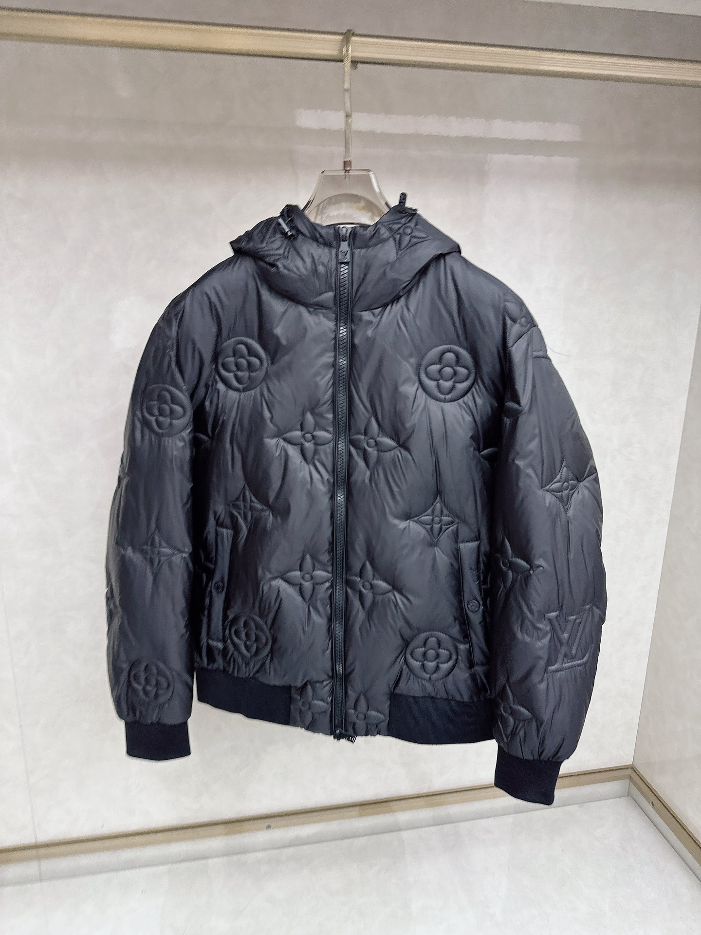NO:627820,LV  The new 2025 autumn and winter down jacket reshapes the winter luxury aesthetics with the iconic Monogram embossed presbyopic pattern. The style adopts a loose silhouette and hooded design, and the whole body is covered with a three-dimensional black embossed presbyopic pattern, giving the whole body a deep and rich texture. The sleeves are embellished with eye-catching colors of the same color  The '' letter logo is a low-key way to highlight the brand's genes. The hem and cuffs are made of stretch rib knitted fabric to enhance the fit and windproof and warm performance. The details are full of ingenuity, the main zipper is smooth and practical, and the label information clearly indicates that the surface is made of high-quality wool, ensuring the high-end texture and comfortable touch of the fabric.  In terms of style, this item perfectly combines the classic heritage of the brand with modern street fashion. The unique embossed pattern and all-black color scheme create a mysterious and powerful aura, with both high-end fashion sense and practical functionality. It can be paired with simple inner wear to create daily looks, or can be layered with brand items to show an overall fashion attitude. It is a trendy masterpiece that combines warmth, recognition and collectible value in autumn and winter. 48-56,, louis vuitton, down jacket, hats, alexander wang19860909LV 2025秋冬新品羽绒服,以标志性Monogram浮雕老花图案重塑冬日奢华美学.款式采用宽松廓形与连帽设计,通体覆盖立体感十足的黑色压花老花图案,赋予整体深邃而丰富的纹理层次.衣袖上点缀醒目的同色''字母标识,低调彰显品牌基因.下摆与袖口采用弹力罗纹针织面料,增强贴合度与防风保暖性能.细节处尽显匠心,主拉链顺滑实用,而标签信息明确标注其表地采用优质羊毛材质,确保了面料的高级质感与舒适触感. 风格上,这款单品将的经典传承与现代街头时尚完美融合.独特的浮雕图案与全黑配色营造出神秘而强大的气场,兼具高端时装感与实穿功能性.它既能搭配简约内搭打造日常造型,亦可与品牌单品叠穿展现整体时尚态度,是秋冬季节兼具保暖性、辨识度与收藏价值的潮流力作.48-56,,louis vuitton,down jacket,hats,alexander wang,Men's clothing