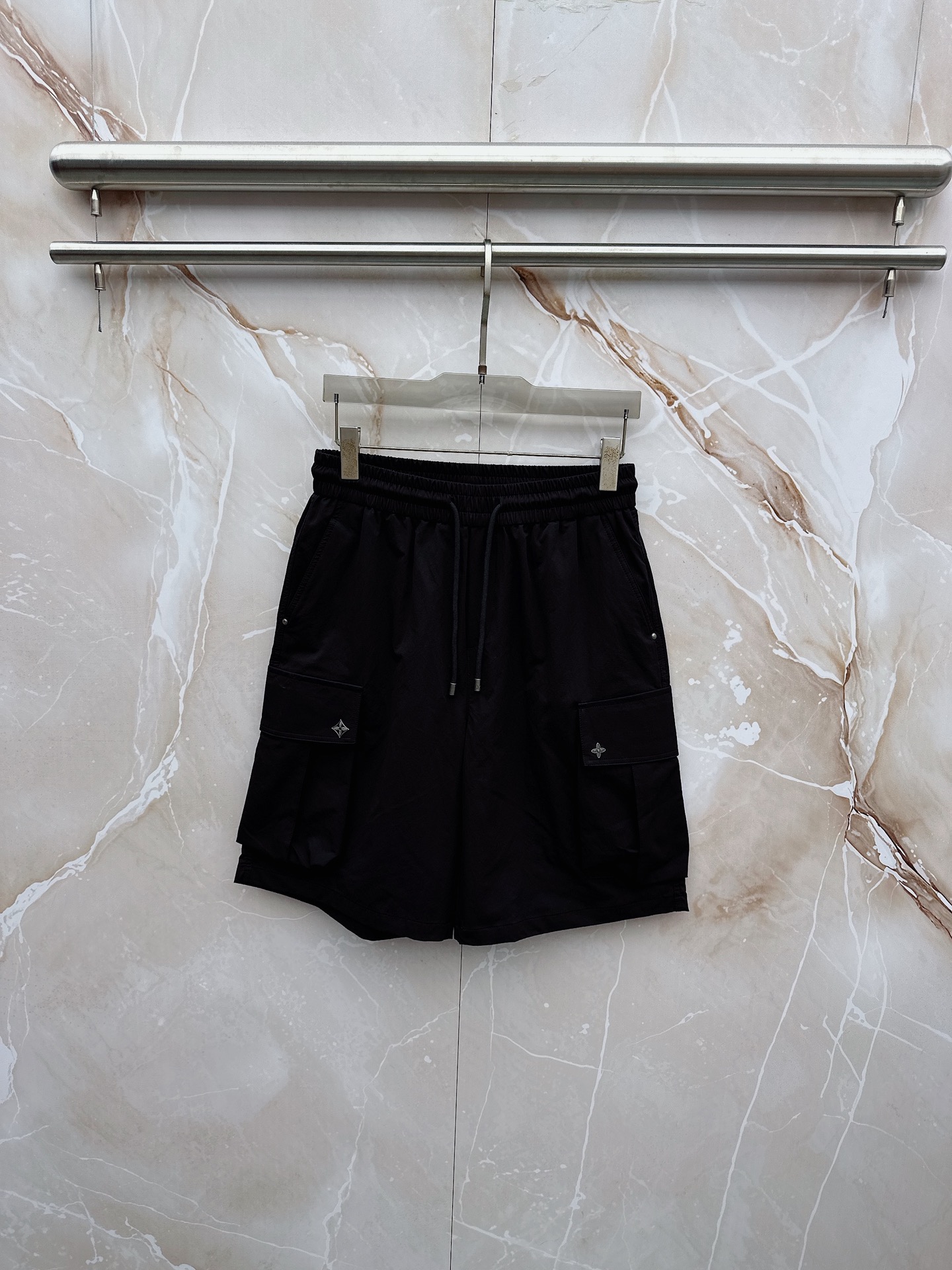 NO:932783,LV 2026 spring and summer new cargo shorts, continuing the classic Cargo  Pocket design, two-dimensional three-dimensional large pockets on both sides combine practicality and style. The drawstring elastic waistband adapts to various body shapes and easily creates a casual street posture. The fabric is made of light and breathable cotton blend material, which is soft and skin-friendly. It is refreshing and not stuffy to wear in spring and summer. The drapey fabric naturally modifies the leg shape and brings a lazy atmosphere when walking. The details are embellished with metal buttons and exquisite brand logos, highlighting quality in a low-key manner. The overall style combines the tough lines of Japanese workwear.  The stripes have a relaxed feel with American casual, with neat silhouettes for outdoor functions without losing the trendy attitude of urban streets. Whether it is daily commuting, weekend outings or sports and fitness, they can be easily controlled and show effortless fashion. In the spring and summer of 2026, let these cargo shorts become a versatile tool in your wardrobe. It uses simple colors and practical designs to interpret the new generation of street aesthetics, and easily wears the perfect balance of high-end and comfort. 29-38, louis  vuitton,shorts,19860909LV 2026春夏新品工装短裤,延续经典Cargo Pocket设计,双侧立体大口袋兼具实用性与造型感,抽绳松紧腰头适配各种身形,轻松打造随性街头姿态.面料选用轻薄透气的棉质混纺材质,触感柔软亲肤,春夏穿着清爽不闷热,垂坠感十足的面料自然修饰腿型,走动间自带慵懒氛围.细节处点缀金属纽扣与精致品牌标识,低调中彰显品质.整体风格融合日系工装的硬朗线条与美式休闲的松弛感,既有户外机能的利落轮廓,又不失都市街头的潮流态度.无论是日常通勤、周末出游还是运动健身,都能轻松驾驭,展现不费力的时髦感.2026春夏,让这条工装短裤成为你衣橱里的百搭利器,用简约色彩与实用设计诠释新一代街头美学,轻松穿出高级感与舒适度的完美平衡.29-38,,louis vuitton,shorts,,Men's clothing