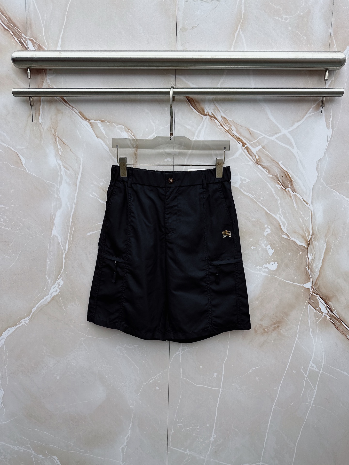 NO:932790,Burberry 2026 spring and summer new cargo shorts continue the classic Cargo  Pocket design, two-dimensional three-dimensional large pockets on both sides combine practicality and style. The drawstring elastic waistband adapts to various body shapes and easily creates a casual street posture. The fabric is made of light and breathable cotton blend material, which is soft and skin-friendly, suitable for spring and summer wear.  The fabric is refreshing and not stuffy, and the drapey fabric naturally modifies the leg shape, giving it a lazy atmosphere when walking. The details are embellished with metal buttons and exquisite brand logos, highlighting quality in a low-key manner. The overall style combines the tough lines of Japanese workwear with American casual  They have a sense of leisure and relaxation, with neat silhouettes for outdoor functions, without losing the trendy attitude of urban streets. Whether it is daily commuting, weekend outings or sports and fitness, they can be easily controlled and show effortless fashion. In the spring and summer of 2026, make these work shorts a versatile tool in your wardrobe. It uses simple colors and practical designs to interpret the new generation of street aesthetics, and easily wears the perfect balance of high-end and comfort. M-4XL,, burberry, shorts,19860909巴宝莉 2026春夏新品工装短裤,延续经典Cargo Pocket设计,双侧立体大口袋兼具实用性与造型感,抽绳松紧腰头适配各种身形,轻松打造随性街头姿态.面料选用轻薄透气的棉质混纺材质,触感柔软亲肤,春夏穿着清爽不闷热,垂坠感十足的面料自然修饰腿型,走动间自带慵懒氛围.细节处点缀金属纽扣与精致品牌标识,低调中彰显品质.整体风格融合日系工装的硬朗线条与美式休闲的松弛感,既有户外机能的利落轮廓,又不失都市街头的潮流态度.无论是日常通勤、周末出游还是运动健身,都能轻松驾驭,展现不费力的时髦感.2026春夏,让这条工装短裤成为你衣橱里的百搭利器,用简约色彩与实用设计诠释新一代街头美学,轻松穿出高级感与舒适度的完美平衡.M-4XL,,burberry,shorts,,Men's clothing