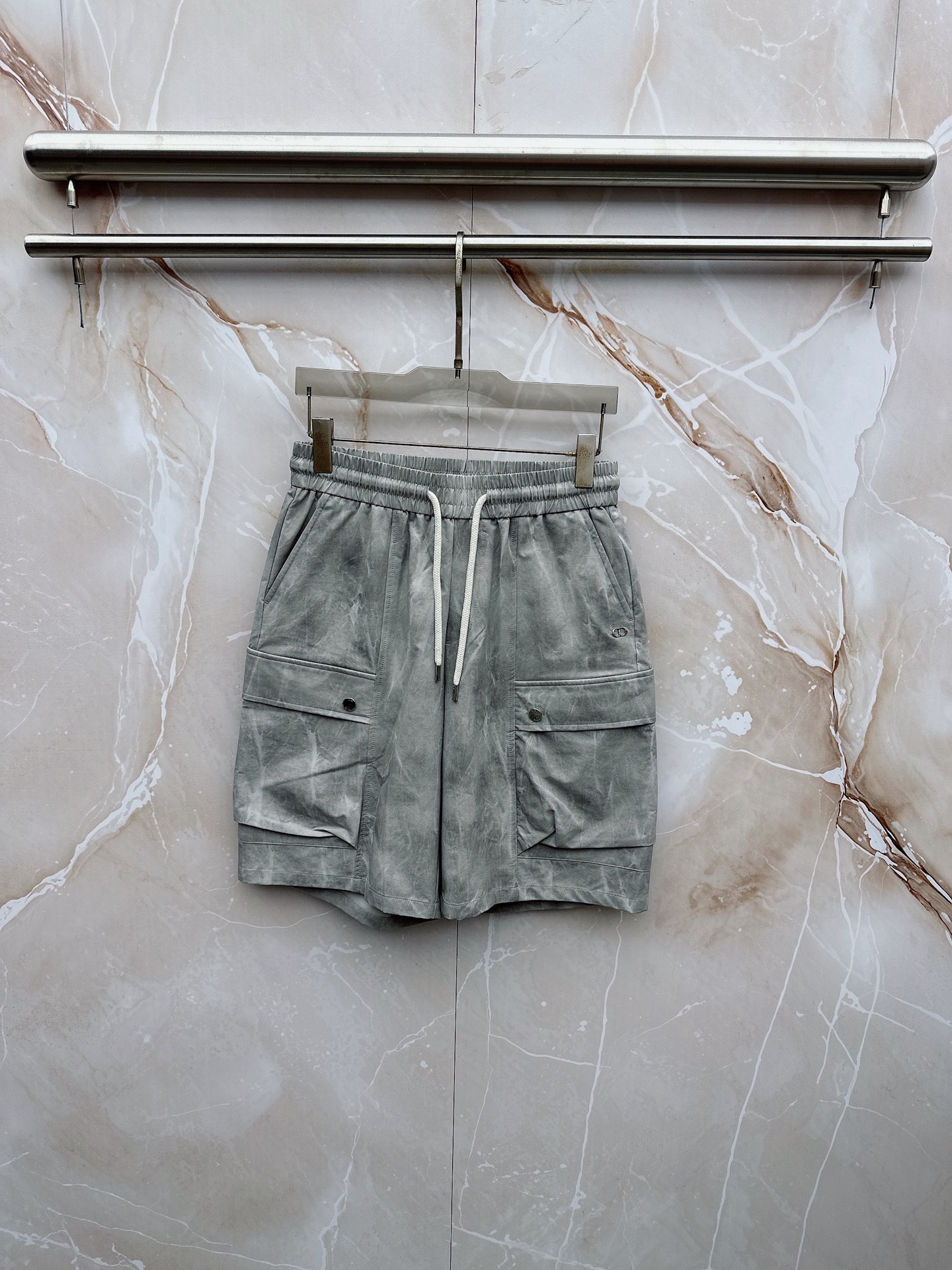 NO:907037,Dior's 2026 spring and summer new cargo shorts continue the classic Cargo  Pocket design, two-dimensional three-dimensional large pockets on both sides combine practicality and style. The drawstring elastic waistband adapts to various body shapes and easily creates a casual street posture. The fabric is made of light and breathable cotton blend material, which is soft and skin-friendly. It is refreshing and not stuffy to wear in spring and summer. The drapey fabric naturally modifies the leg shape and brings a lazy atmosphere when walking. The details are embellished with metal buttons and exquisite brand logos, highlighting quality in a low-key manner. The overall style combines the tough lines and beauty of Japanese workwear.  They have a casual and relaxed feel, with neat silhouettes for outdoor functions without losing the trendy attitude of urban streets. Whether it is daily commuting, weekend outings or sports and fitness, they can be easily controlled and show effortless fashion. In the spring and summer of 2026, make these cargo shorts a versatile tool in your wardrobe. It interprets the new generation of street aesthetics with simple colors and practical design, and can easily wear it to achieve the perfect balance of high-end and comfort. M-4XL,, dior, shorts,19860909迪奥 2026春夏新品工装短裤,延续经典Cargo Pocket设计,双侧立体大口袋兼具实用性与造型感,抽绳松紧腰头适配各种身形,轻松打造随性街头姿态.面料选用轻薄透气的棉质混纺材质,触感柔软亲肤,春夏穿着清爽不闷热,垂坠感十足的面料自然修饰腿型,走动间自带慵懒氛围.细节处点缀金属纽扣与精致品牌标识,低调中彰显品质.整体风格融合日系工装的硬朗线条与美式休闲的松弛感,既有户外机能的利落轮廓,又不失都市街头的潮流态度.无论是日常通勤、周末出游还是运动健身,都能轻松驾驭,展现不费力的时髦感.2026春夏,让这条工装短裤成为你衣橱里的百搭利器,用简约色彩与实用设计诠释新一代街头美学,轻松穿出高级感与舒适度的完美平衡.M-4XL,,dior,shorts,,Men's clothing