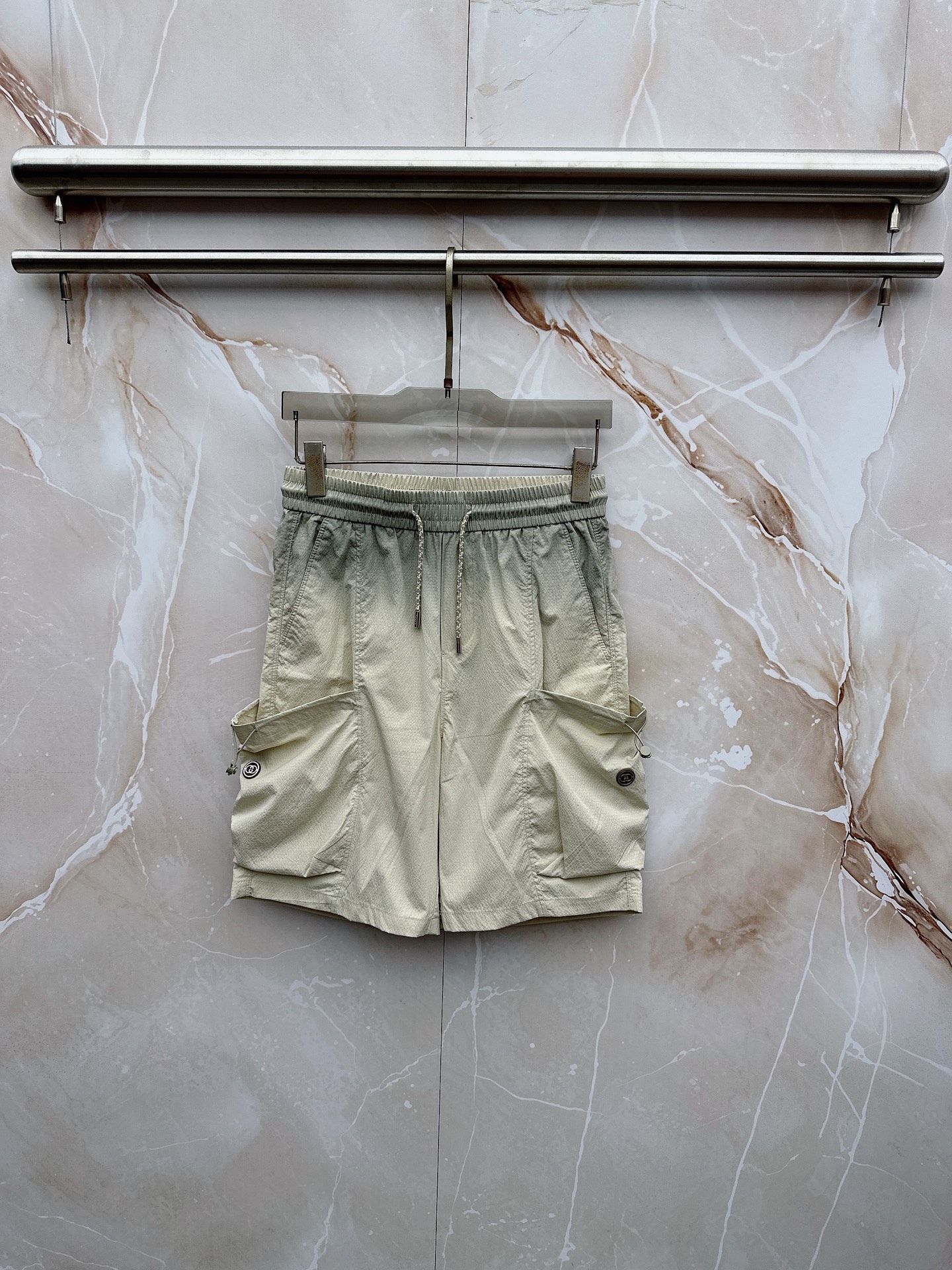 NO:913255,Gucci 2026 spring and summer new cargo shorts, continuing the classic Cargo  Pocket design, two-dimensional three-dimensional large pockets on both sides combine practicality and style. The drawstring elastic waistband adapts to various body shapes and easily creates a casual street posture. The fabric is made of light and breathable cotton blend material, which is soft and skin-friendly. It is refreshing and not stuffy to wear in spring and summer. The drapey fabric naturally modifies the leg shape and brings a lazy atmosphere when walking. The details are embellished with metal buttons and exquisite brand logos, highlighting quality in a low-key manner. The overall style combines the tough lines of Japanese workwear.  With the relaxed feel of American casual, it has the neat silhouette of outdoor functions without losing the trendy attitude of urban streets. Whether it is daily commuting, weekend outings or sports and fitness, it can be easily controlled and shows an effortless sense of fashion. In the spring and summer of 2026, let these cargo shorts become a versatile tool in your wardrobe. It interprets the new generation of street aesthetics with simple colors and practical design, and can easily wear the perfect balance of high-end and comfort. M-4XL,, shorts,19860909古奇 2026春夏新品工装短裤,延续经典Cargo Pocket设计,双侧立体大口袋兼具实用性与造型感,抽绳松紧腰头适配各种身形,轻松打造随性街头姿态.面料选用轻薄透气的棉质混纺材质,触感柔软亲肤,春夏穿着清爽不闷热,垂坠感十足的面料自然修饰腿型,走动间自带慵懒氛围.细节处点缀金属纽扣与精致品牌标识,低调中彰显品质.整体风格融合日系工装的硬朗线条与美式休闲的松弛感,既有户外机能的利落轮廓,又不失都市街头的潮流态度.无论是日常通勤、周末出游还是运动健身,都能轻松驾驭,展现不费力的时髦感.2026春夏,让这条工装短裤成为你衣橱里的百搭利器,用简约色彩与实用设计诠释新一代街头美学,轻松穿出高级感与舒适度的完美平衡.M-4XL,,shorts,,Men's clothing