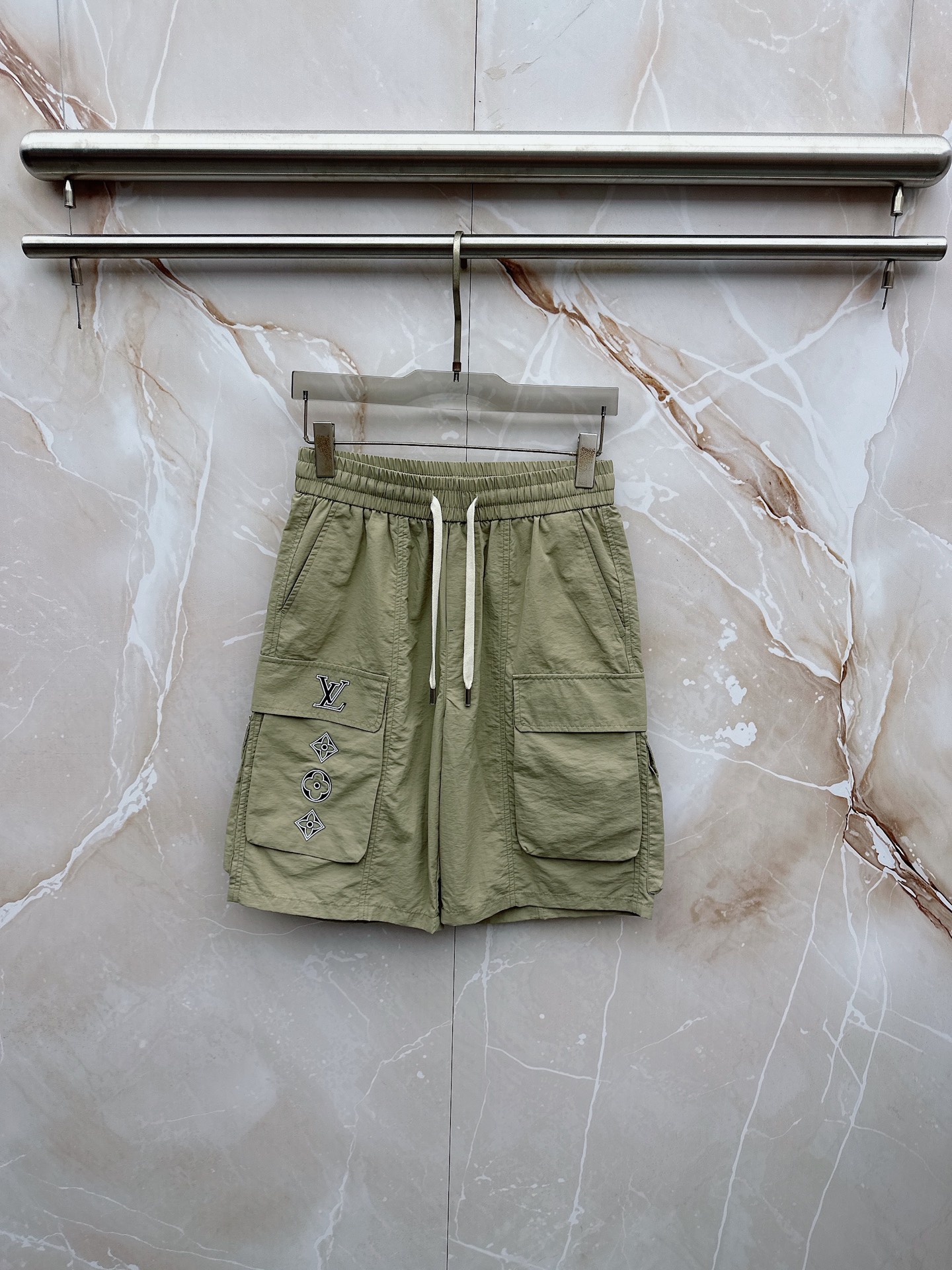 NO:913253,LV 2026 spring and summer new cargo shorts, continuing the classic Cargo  Pocket design, two-dimensional three-dimensional large pockets on both sides combine practicality and style. The drawstring elastic waistband adapts to various body shapes and easily creates a casual street posture. The fabric is made of light and breathable cotton blend material, which is soft and skin-friendly. It is refreshing and not stuffy to wear in spring and summer. The drapey fabric naturally modifies the leg shape and brings a lazy atmosphere when walking. The details are embellished with metal buttons and exquisite brand logos, highlighting quality in a low-key manner. The overall style combines the tough lines of Japanese workwear.  The stripes have a relaxed feel with American leisure, with neat silhouettes for outdoor functions without losing the trendy attitude of urban streets. Whether it is daily commuting, weekend outings or sports and fitness, they can be easily controlled and show effortless fashion. In the spring and summer of 2026, let these cargo shorts become a versatile tool in your wardrobe. It uses simple colors and practical designs to interpret the new generation of street aesthetics, and easily wears the perfect balance of high-end and comfort. M-4XL, Louis  vuitton,shorts,19860909LV 2026春夏新品工装短裤,延续经典Cargo Pocket设计,双侧立体大口袋兼具实用性与造型感,抽绳松紧腰头适配各种身形,轻松打造随性街头姿态.面料选用轻薄透气的棉质混纺材质,触感柔软亲肤,春夏穿着清爽不闷热,垂坠感十足的面料自然修饰腿型,走动间自带慵懒氛围.细节处点缀金属纽扣与精致品牌标识,低调中彰显品质.整体风格融合日系工装的硬朗线条与美式休闲的松弛感,既有户外机能的利落轮廓,又不失都市街头的潮流态度.无论是日常通勤、周末出游还是运动健身,都能轻松驾驭,展现不费力的时髦感.2026春夏,让这条工装短裤成为你衣橱里的百搭利器,用简约色彩与实用设计诠释新一代街头美学,轻松穿出高级感与舒适度的完美平衡.M-4XL,,louis vuitton,shorts,,Men's clothing