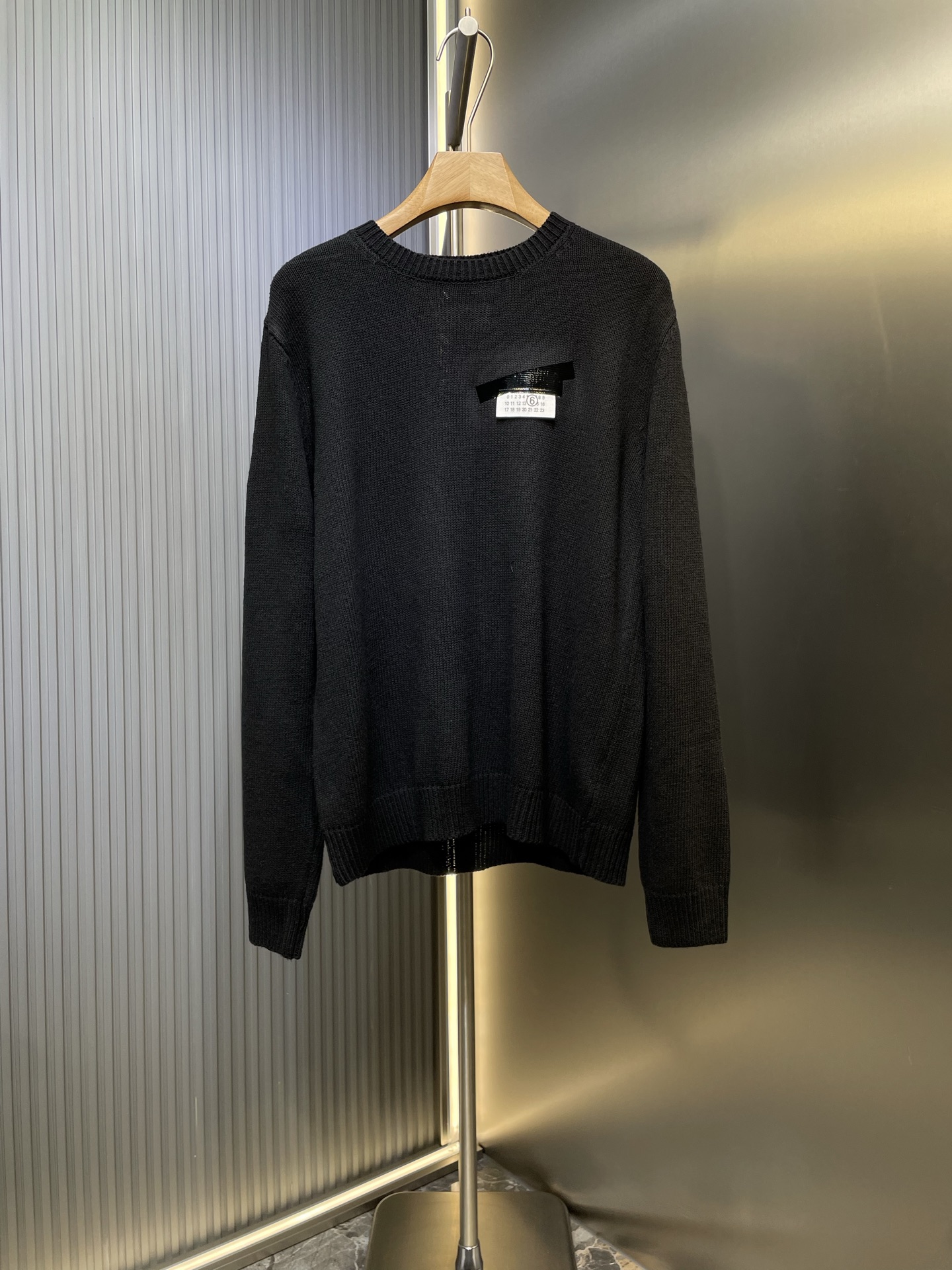 NO:550554,Martin Margiel* 25FW MM6 tape label wool blend sweater The main body is made of high-split, high-density wool blend yarn. The custom multi-layer lettering film is ironed on the chest. The hot film used is specially treated to give it a PVC texture shiny gloss, perfectly simulates the visual effect of black tape covering the paper label. Its thickness and flexibility are accurately calculated to ensure that it can naturally bend and not crack with the fabric when worn. sizes m l,,masion margiela,masion margiela,sweaters,alexander wang19860909Martin Margiel*马吉拉 25FW MM6胶带标签羊毛混纺毛衣 主体采用高支数、高密度的羊毛混纺纱线精纺而成. 胸前定制多层刻字膜烫画工艺,所使用的烫画膜料本身经过特殊处理,使其呈现出PVC质感的微光泽,完美模拟了黑色胶带覆盖在纸张标签上的视觉效果.其厚度和柔韧性经过精确计算,确保在穿着时能随面料自然弯曲而非开裂. sizes m l,,masion margiela,masion margiela,sweaters,alexander wang,Men's clothing