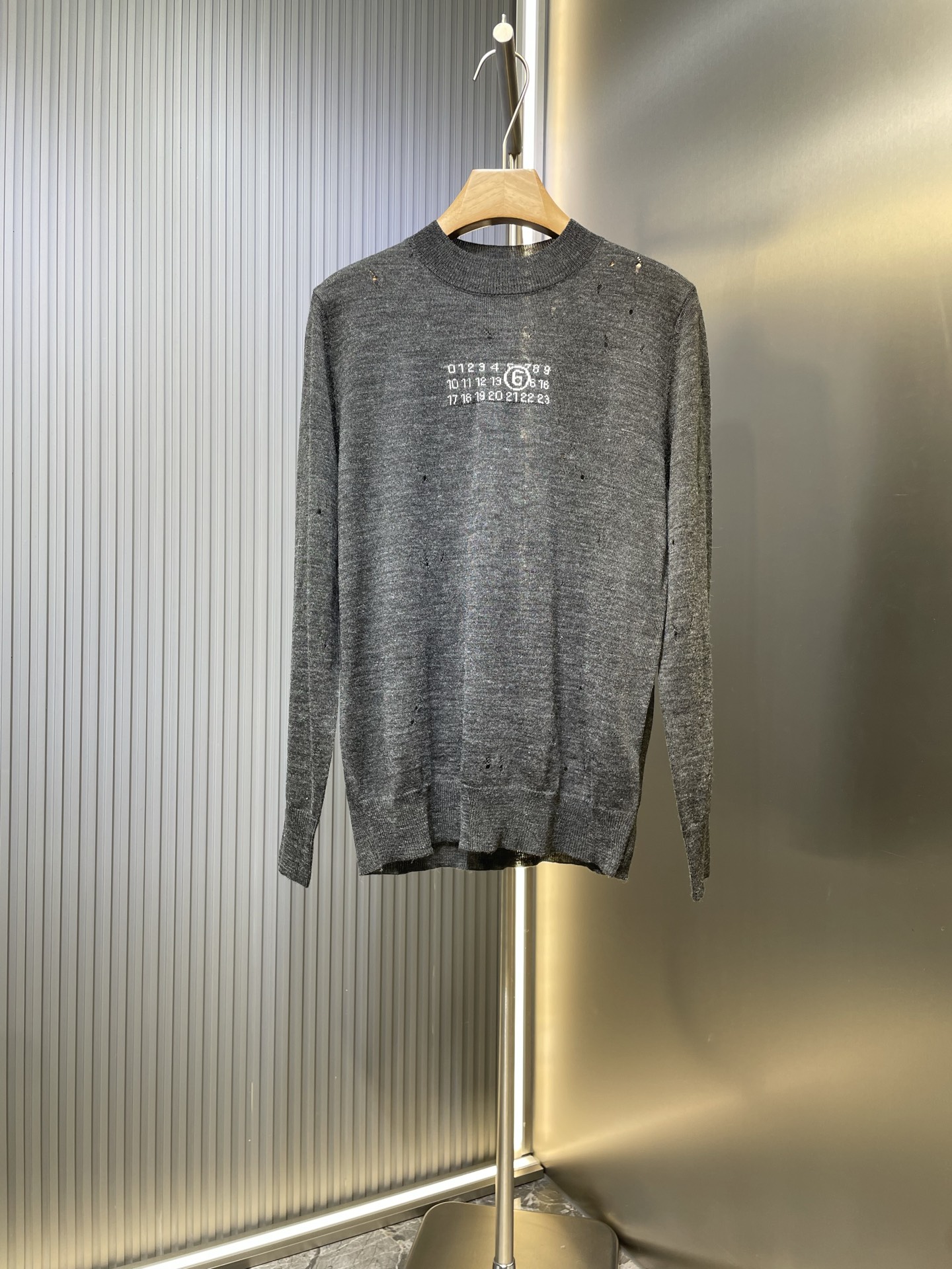 NO:550562,Martin Margiel* 25FW MM6 Destruction Jacquard Wool Blended Sweater Deposit Spinning Special Gray Yarn, whose gray color is not an ordinary color, but a special gray yarn specially designed for defining. The chest pattern adopts precision jacquard technology, woven at one time, rather than post-printing and dyeing. All destruction treatments are done by craftsmen after the sweater is completely woven into shape. This is essentially different from the simple method of 'breaking first and weaving', requiring craftsmen to have an extreme understanding of the tension, elasticity and dispersion of the knitted structure. SizeSML,,masion margiela,masion margiela,sweaters,alexander wang19860909Martin Margiel*马吉拉 25FW MM6破坏提花羊毛混纺毛衣 定纺特殊灰色纱线,其灰色绝非普通色号,而是专门定纺的特殊灰度纱线.胸前图案采用精密提花工艺,一次性织就,而非后期印染. 所有破坏处理都是在毛衣完全织造成型后,由工匠手工完成的.这与“先破再织”的简单方式有本质区别,要求工匠对针织结构的张力、弹性和脱散性有极致理解. SizeSML,,masion margiela,masion margiela,sweaters,alexander wang,Men's clothing