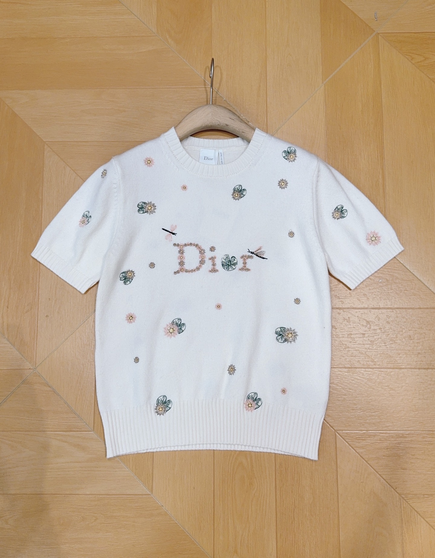 D家新品奶白色细针织短袖，软糯垂顺。衣身点缀手工彩色花卉与蜻蜓刺绣，中心水钻串珠字母精致闪耀，罗纹圆领与收边，版型利落不