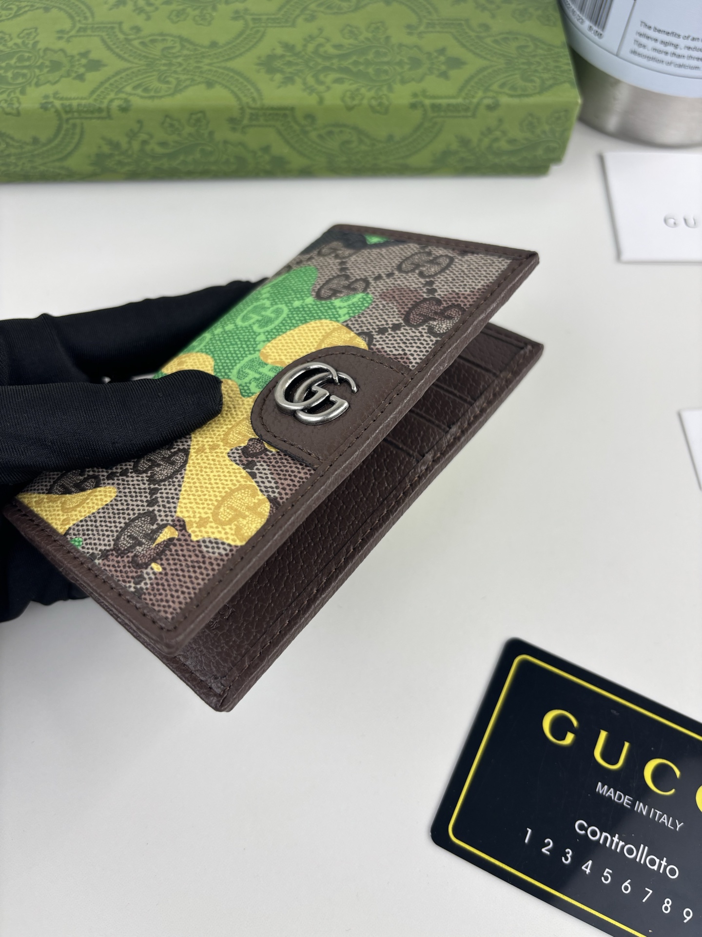 GUCCl生动迷彩结合别致配色，焕新演绎经典GG图案。这款长款卡片夹以大理石纹GG字母图案涂层织物打造，匠心融蕴双G细节