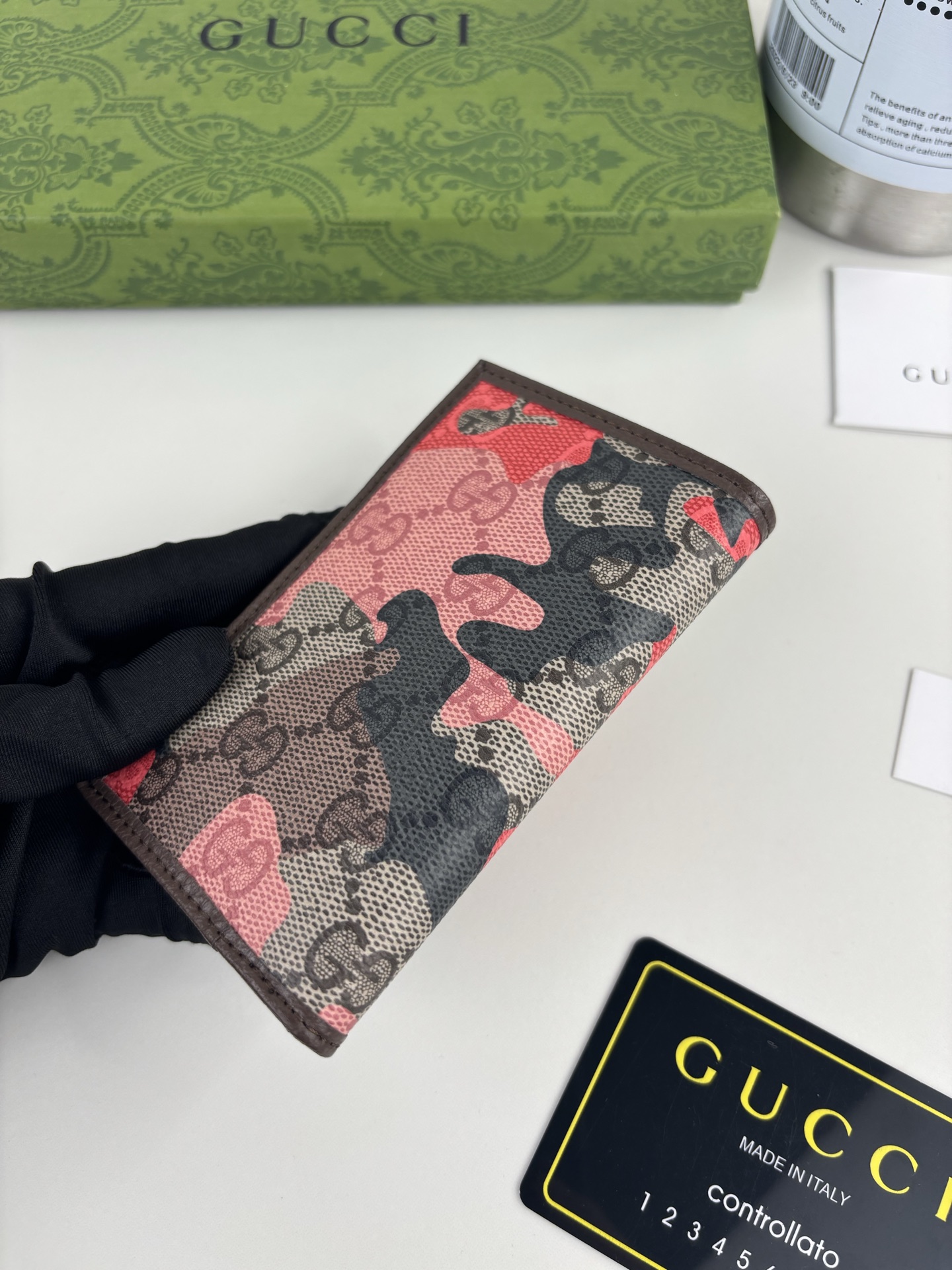 GUCCl生动迷彩结合别致配色，焕新演绎经典GG图案。这款长款卡片夹以大理石纹GG字母图案涂层织物打造，匠心融蕴双G细节