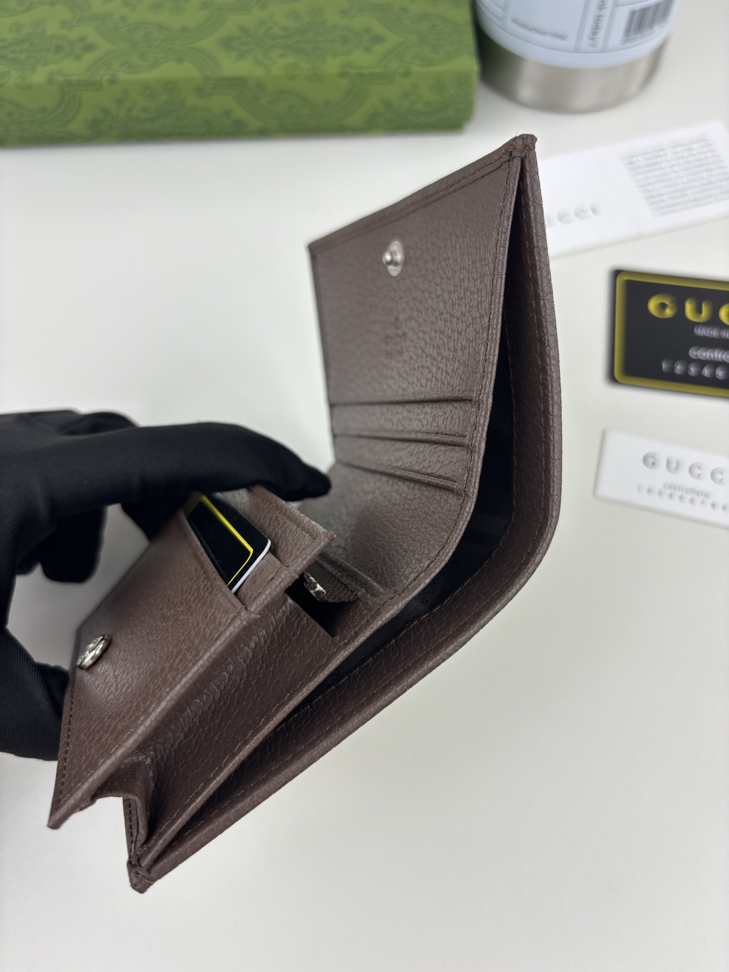 GUCCl生动迷彩结合别致配色，焕新演绎经典GG图案。这款短款卡包以大理石纹GG字母图案涂层织物打造，匠心融蕴双G细节。