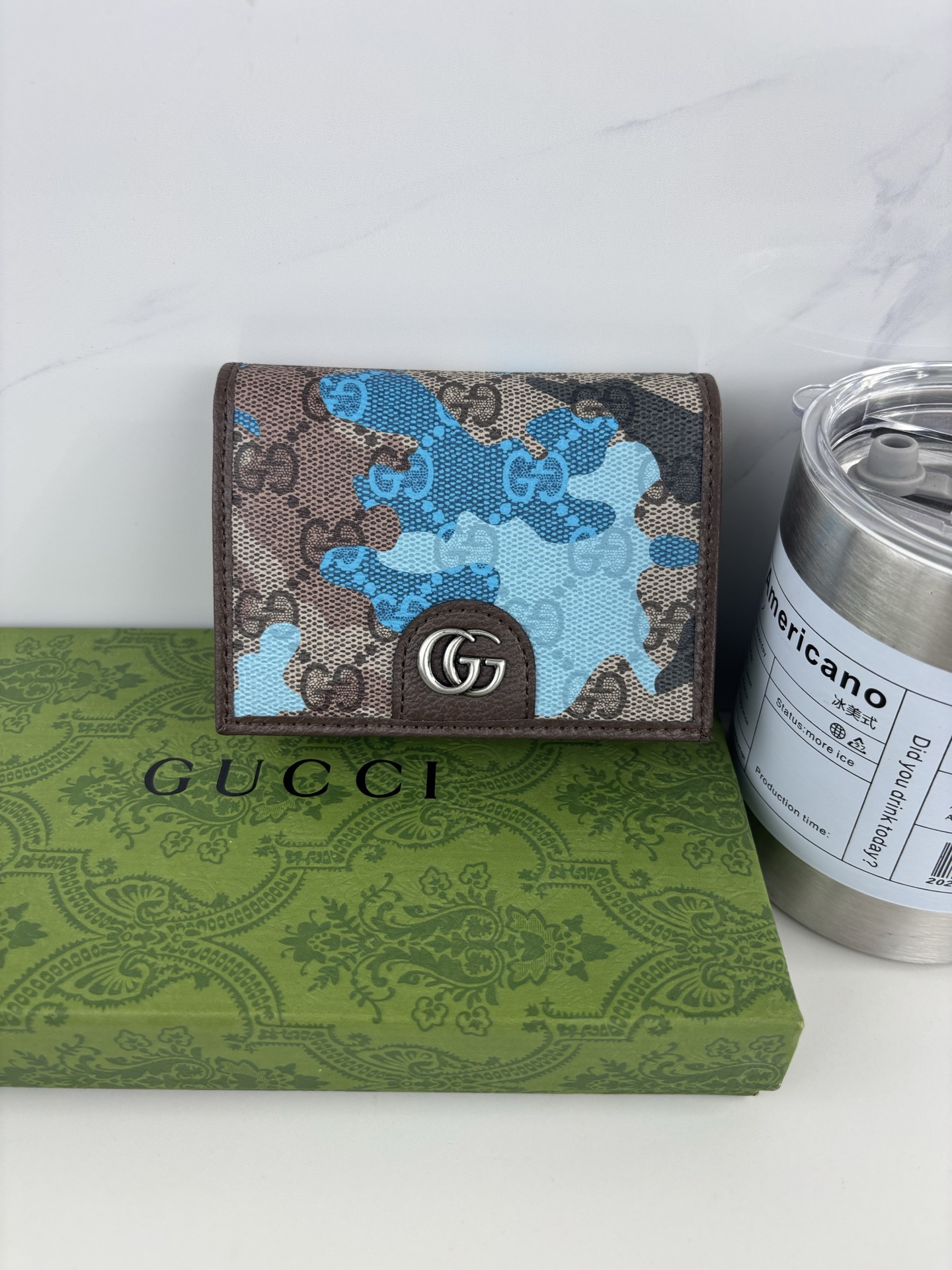 GUCCl生动迷彩结合别致配色，焕新演绎经典GG图案。这款短款卡包以大理石纹GG字母图案涂层织物打造，匠心融蕴双G细节。