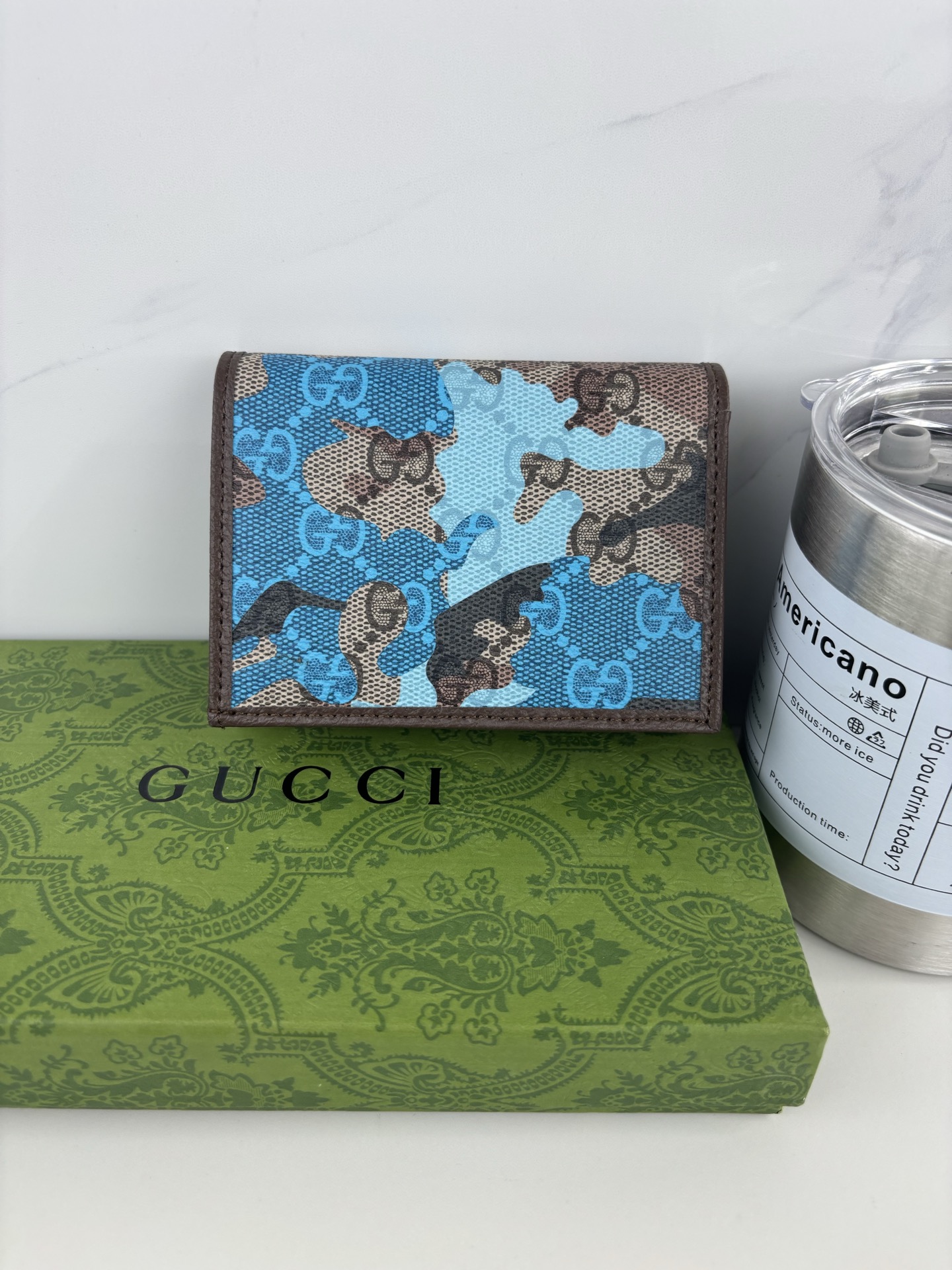 GUCCl生动迷彩结合别致配色，焕新演绎经典GG图案。这款短款卡包以大理石纹GG字母图案涂层织物打造，匠心融蕴双G细节。