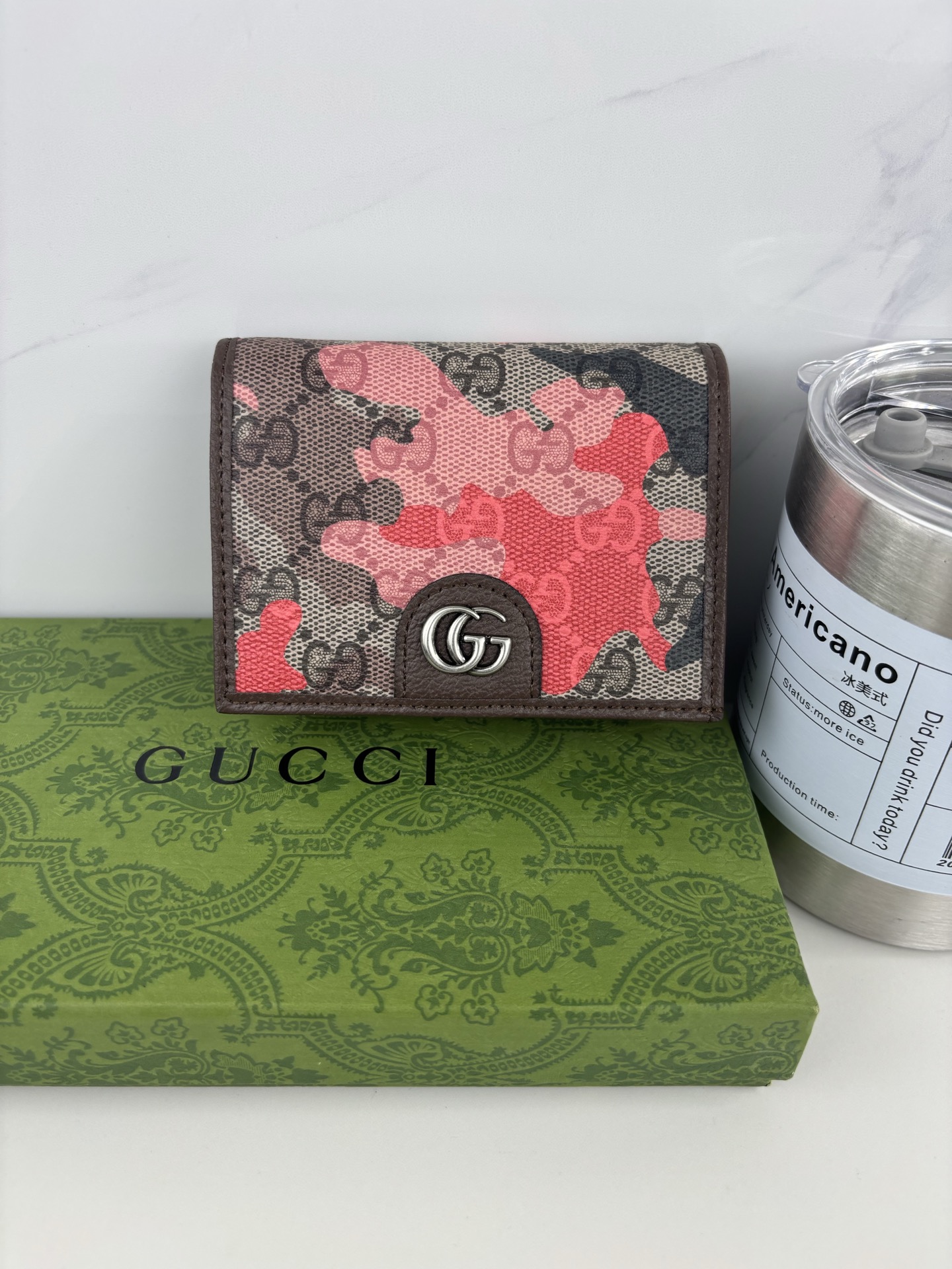 GUCCl生动迷彩结合别致配色，焕新演绎经典GG图案。这款短款卡包以大理石纹GG字母图案涂层织物打造，匠心融蕴双G细节。