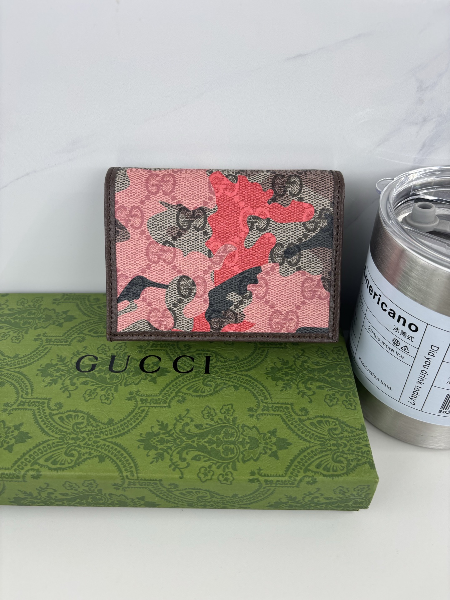 GUCCl生动迷彩结合别致配色，焕新演绎经典GG图案。这款短款卡包以大理石纹GG字母图案涂层织物打造，匠心融蕴双G细节。