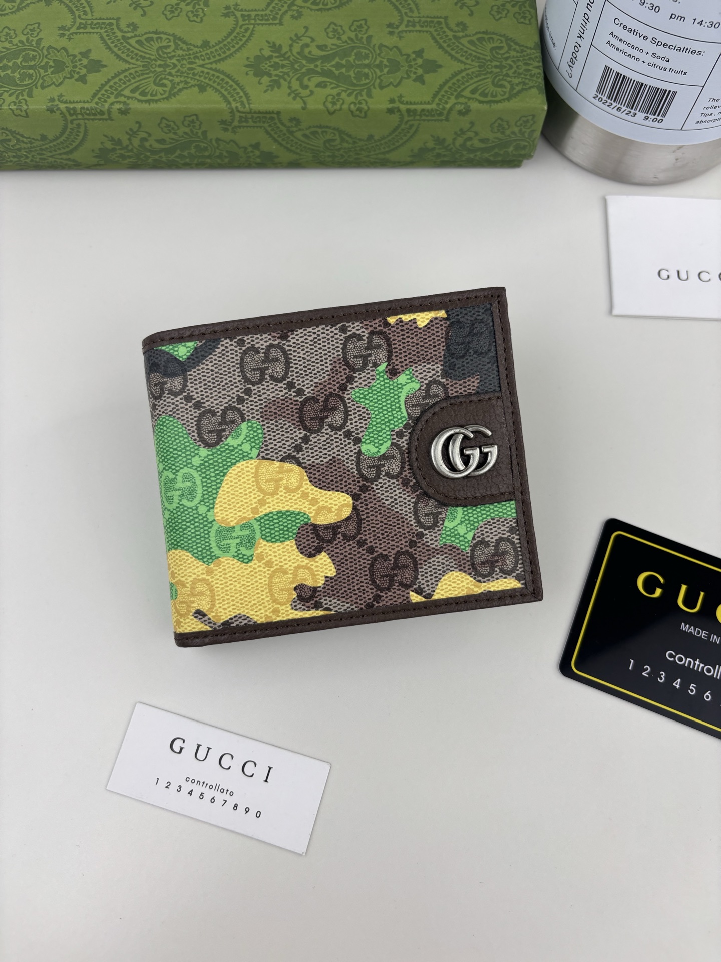 GUCCl生动迷彩结合别致配色，焕新演绎经典GG图案。这款双折包以大理石纹GG字母图案涂层织物打造，匠心融蕴双G细节。 