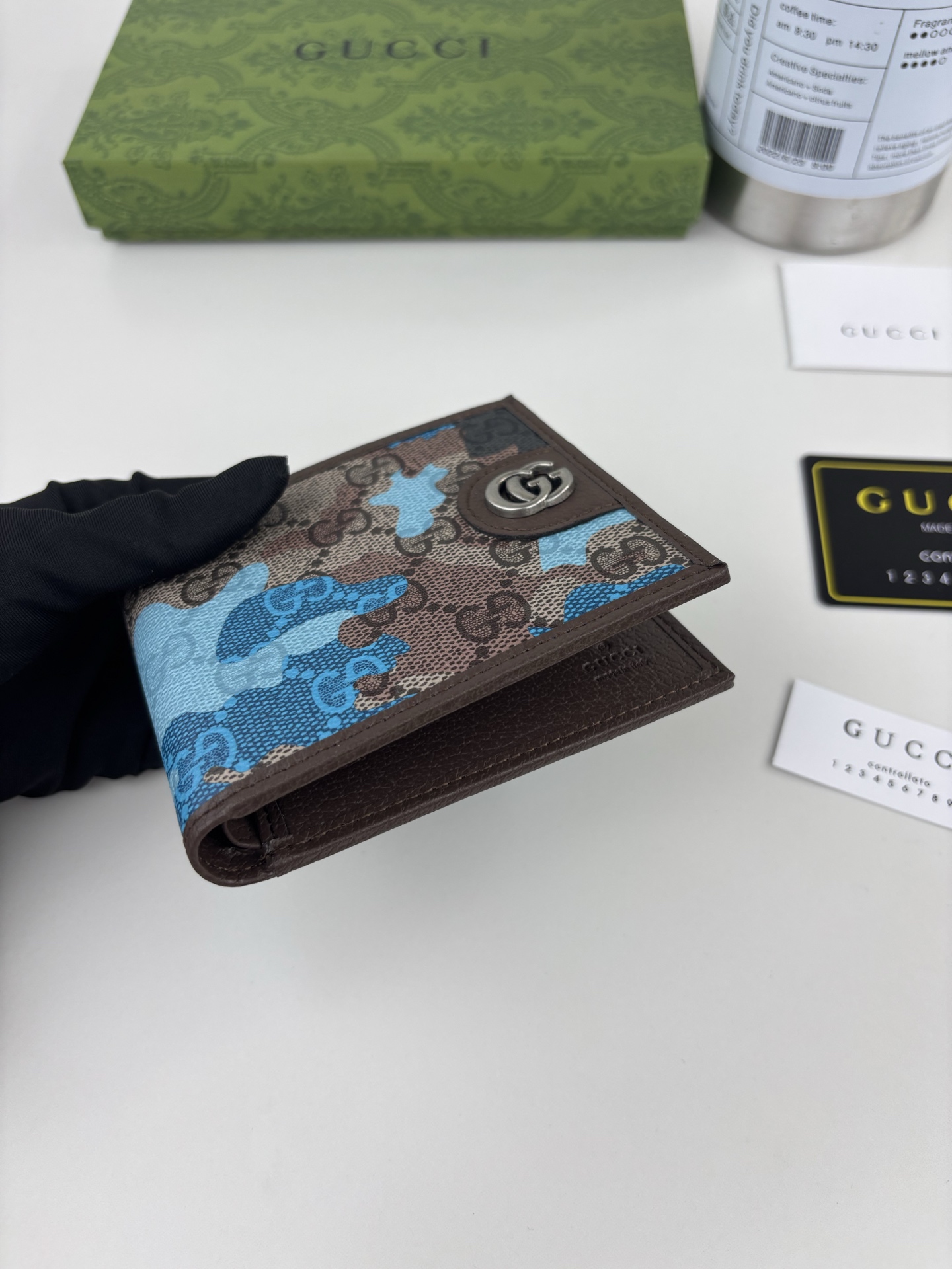 GUCCl生动迷彩结合别致配色，焕新演绎经典GG图案。这款双折包以大理石纹GG字母图案涂层织物打造，匠心融蕴双G细节。 