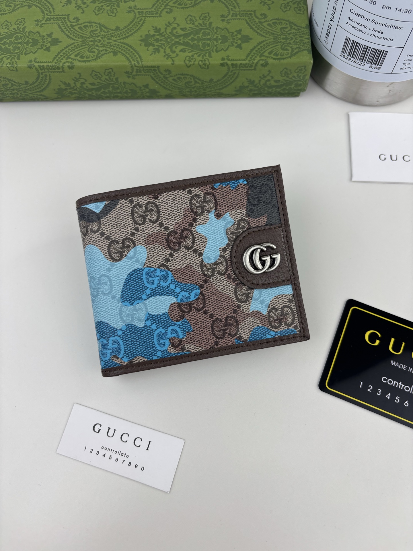 GUCCl生动迷彩结合别致配色，焕新演绎经典GG图案。这款双折包以大理石纹GG字母图案涂层织物打造，匠心融蕴双G细节。 