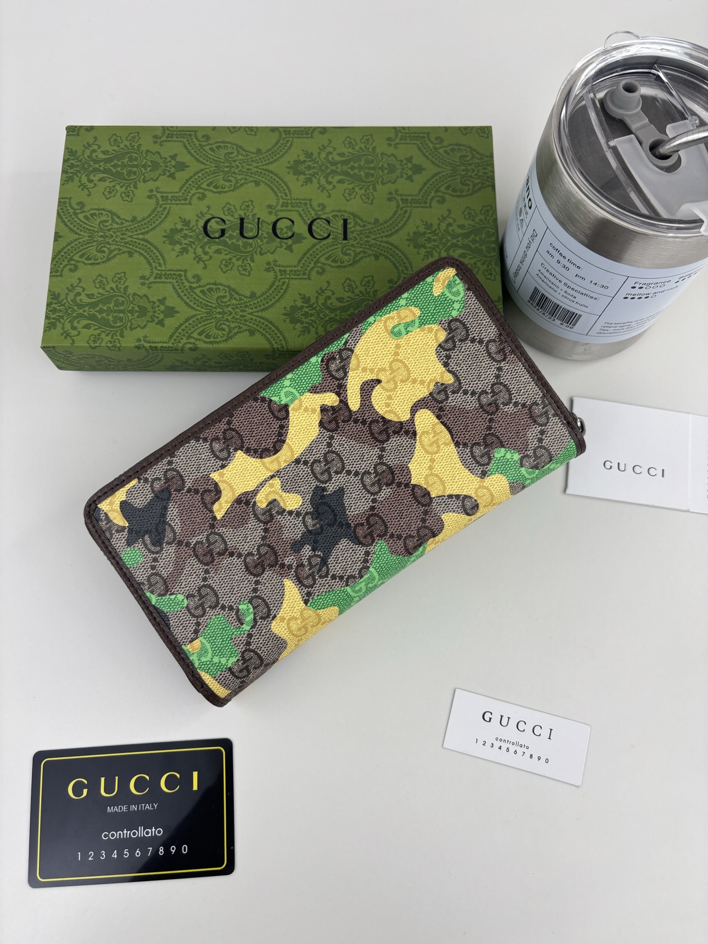 GUCCl生动迷彩结合别致配色，焕新演绎经典GG图案。这款全拉链钱包以大理石纹GG字母图案涂层织物打造，匠心融蕴双G细节