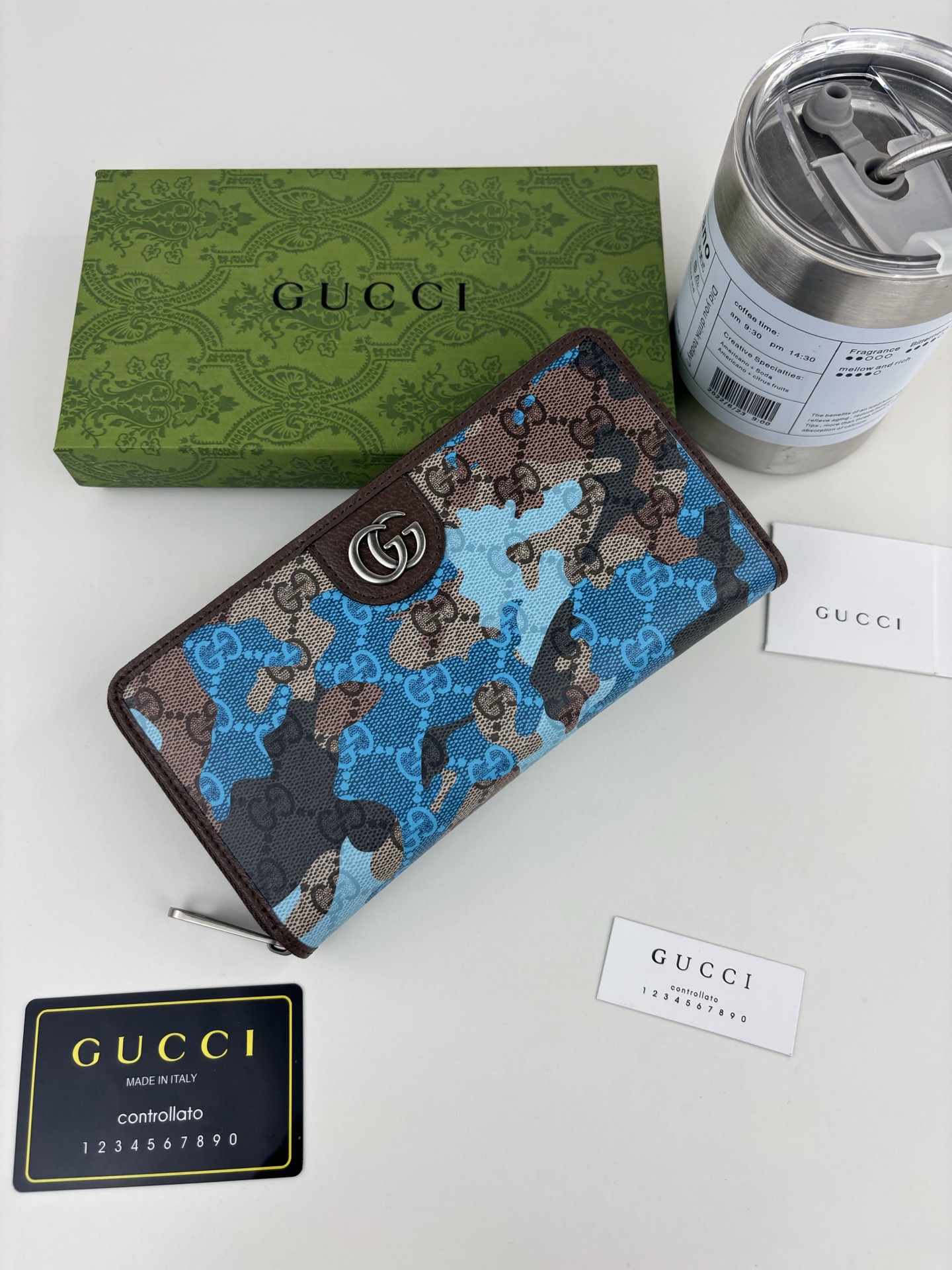 GUCCl生动迷彩结合别致配色，焕新演绎经典GG图案。这款全拉链钱包以大理石纹GG字母图案涂层织物打造，匠心融蕴双G细节
