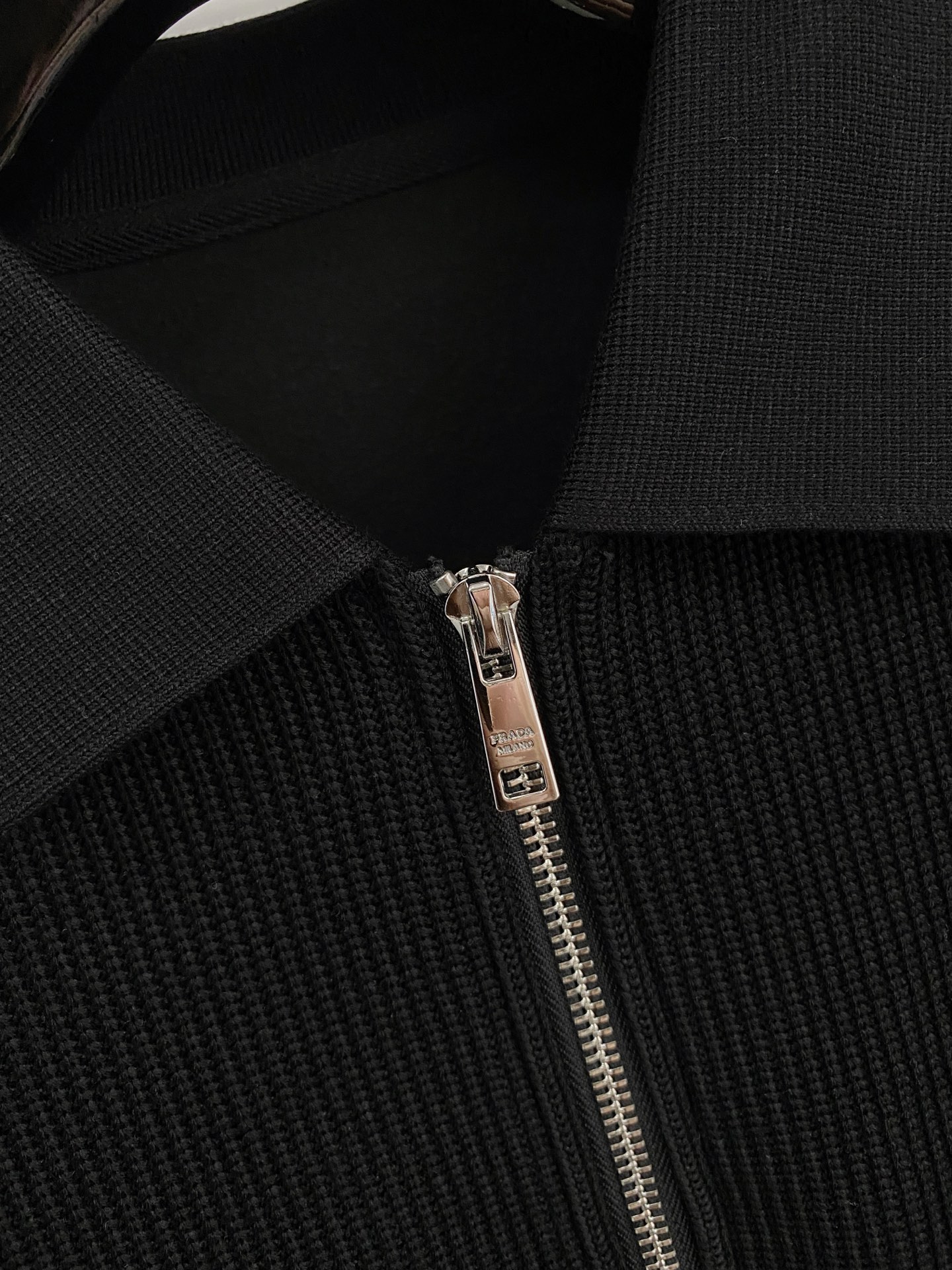 。普拉达 2025秋冬  羊毛混纺套头针织卫衣  几何拼皮的口袋设计 很有亮点，标志字母纽扣 细节上凸显