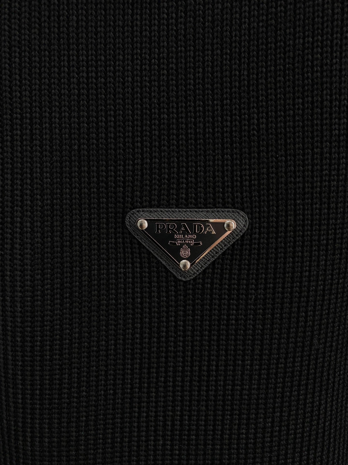 。普拉达 2025秋冬  羊毛混纺套头针织卫衣  几何拼皮的口袋设计 很有亮点，标志字母纽扣 细节上凸显