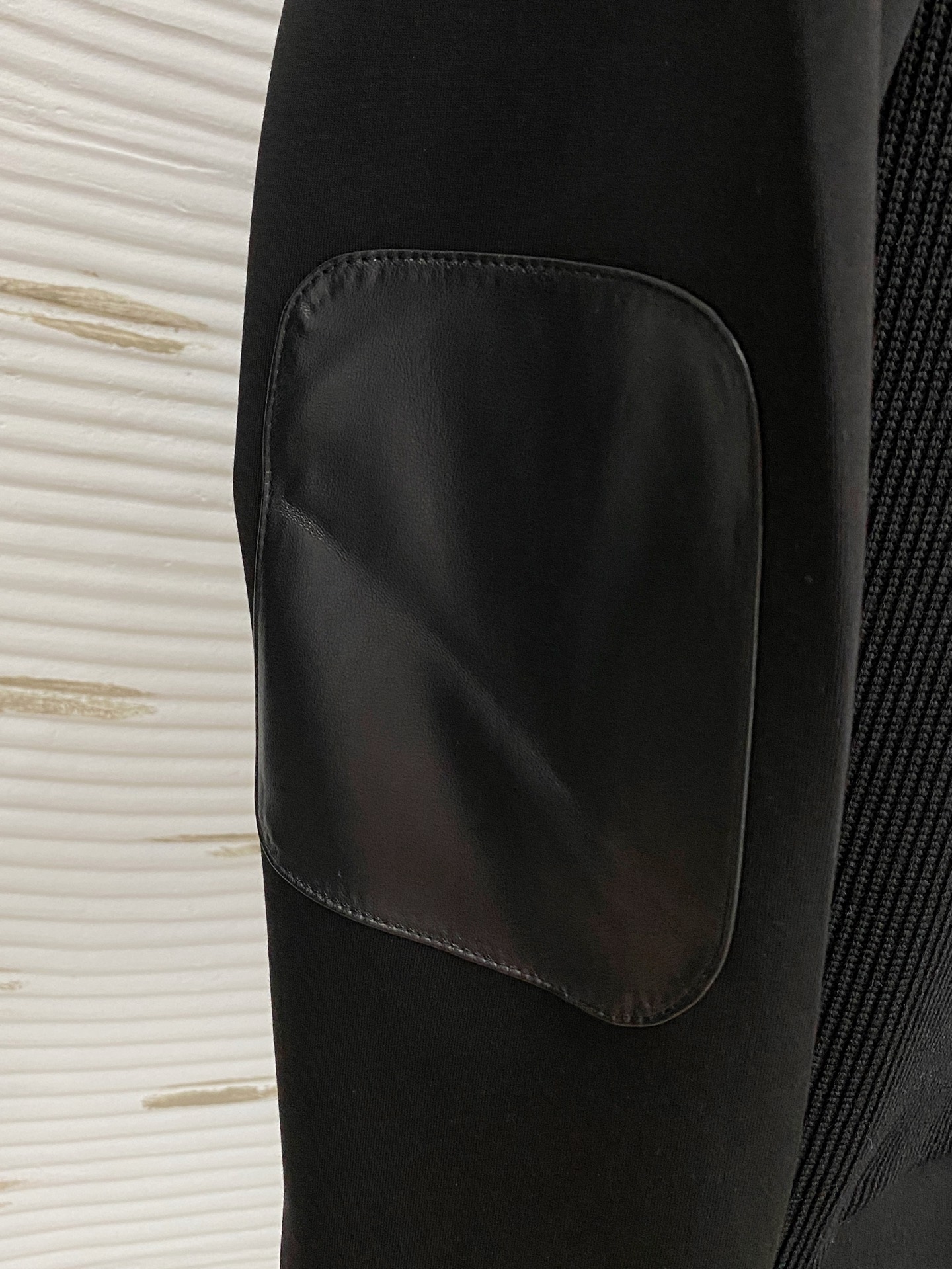 。普拉达 2025秋冬  羊毛混纺套头针织卫衣  几何拼皮的口袋设计 很有亮点，标志字母纽扣 细节上凸显