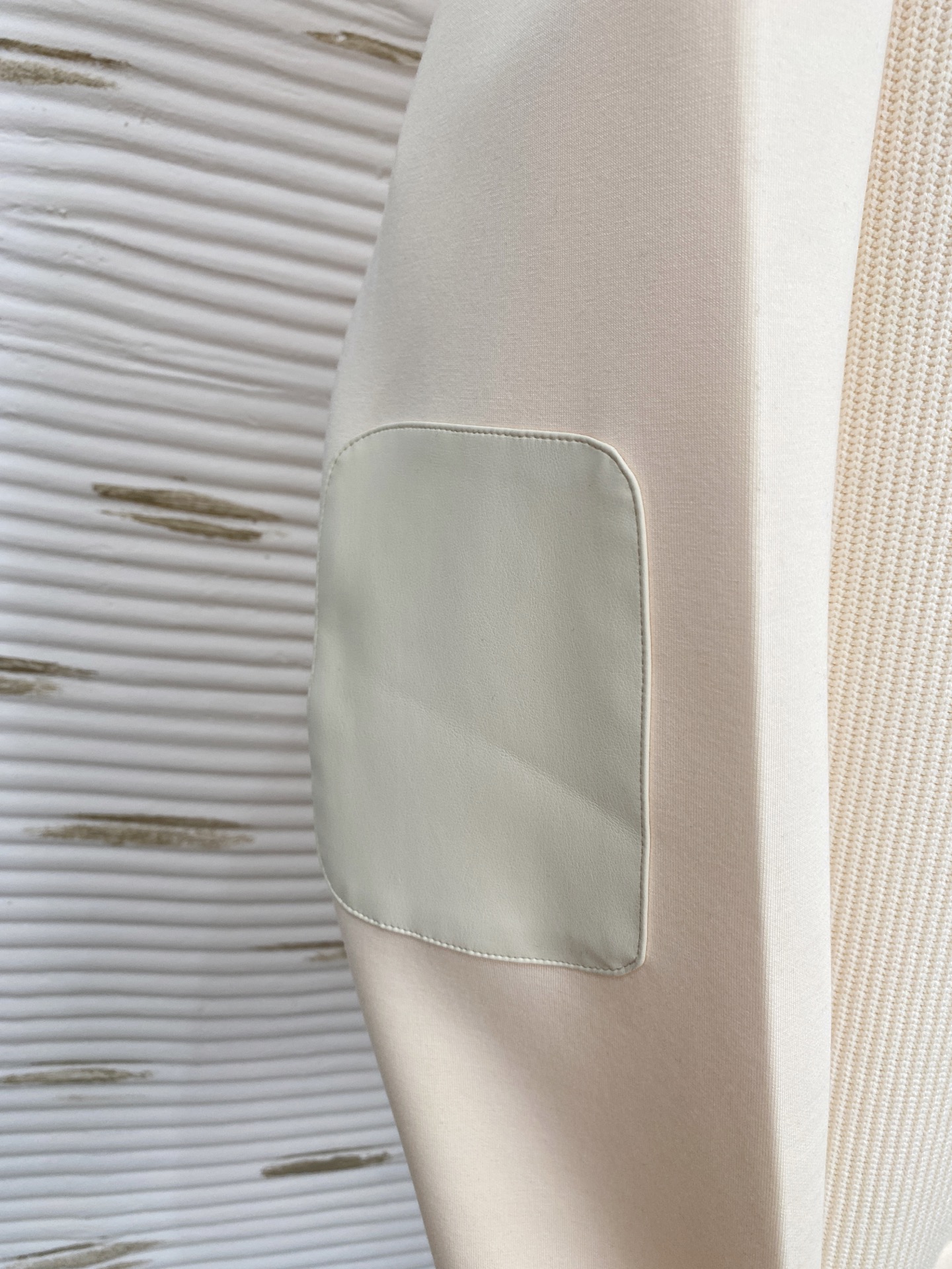 。普拉达 2025秋冬  羊毛混纺套头针织卫衣  几何拼皮的口袋设计 很有亮点，标志字母纽扣 细节上凸显