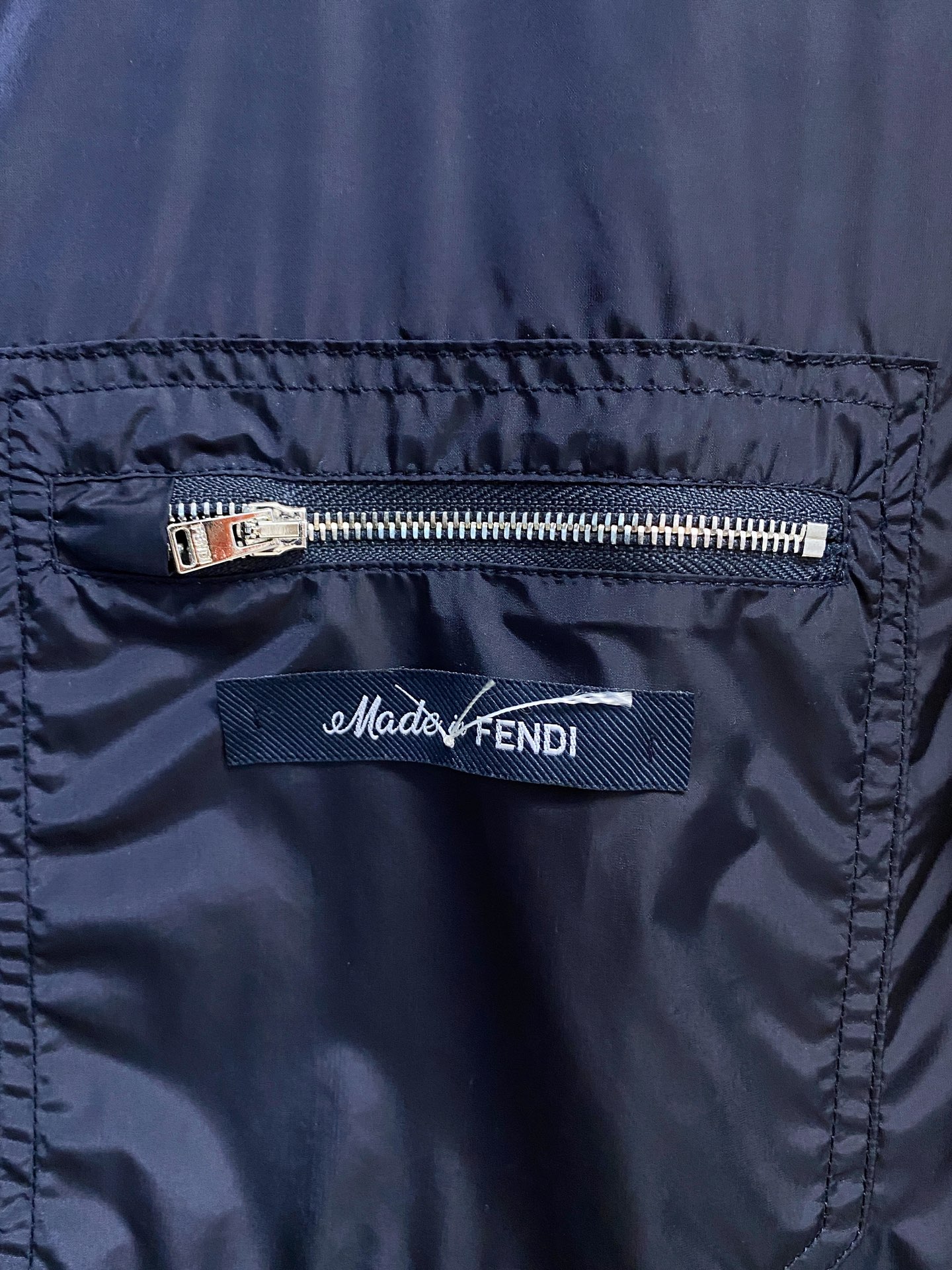 兜帽和侧边拉链口袋风衣。松紧袖口和抽绳下摆。双头拉链开合。蓝色尼龙材质。胸前拉链袋饰有相搭的“Made 