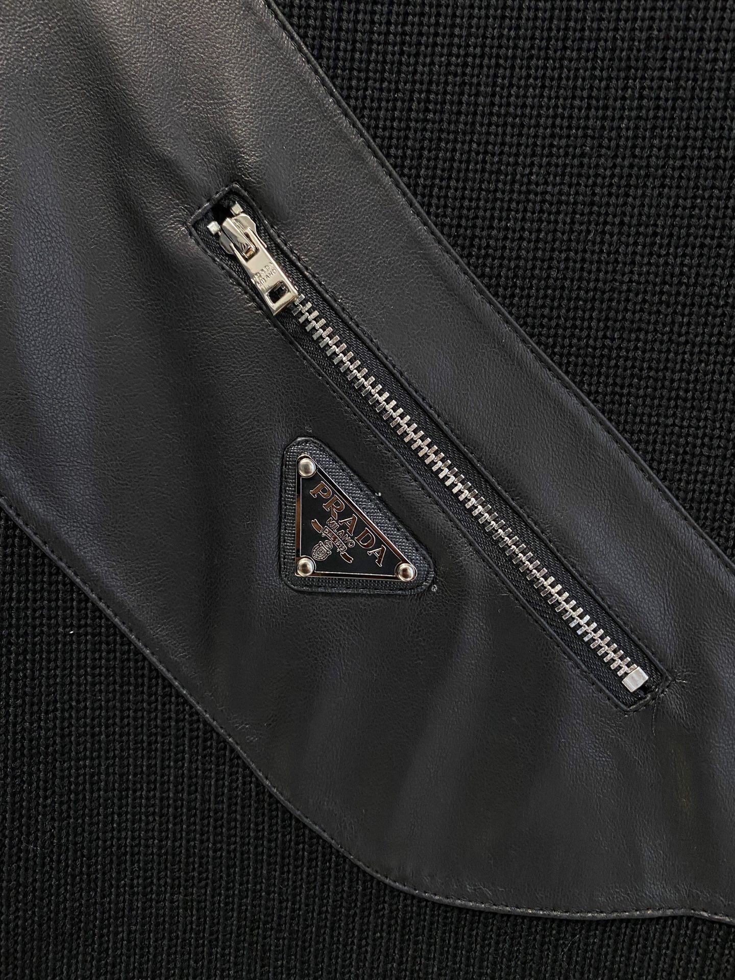 。普拉达 2025秋冬  羊毛混纺套头针织卫衣  几何拼皮的口袋设计 很有亮点，标志字母纽扣 细节上凸显