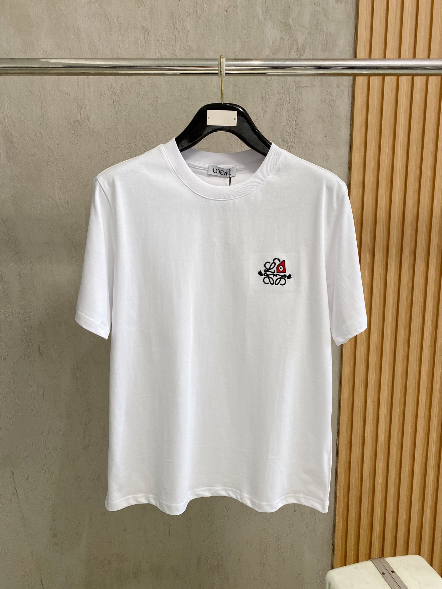 NO:834486,The iconic Anagram eyes embroidered short-sleeved T-shirt from the LOEW_2026 spring and summer series. There is the LOEWE brand logo on the neckline, and the chest is embroidered with a combination of the brand's classic Anagram pattern and the single-eye triangle pattern, which is the core of the series' recognition. It has a classic round neck, is not flattering on the figure, and is a basic model for men and women. Fabric features: The fabric is cotton, soft to the skin, breathable and sweat-absorbent, suitable for spring and summer wear.  The artistic logo combines LOEWE's iconic Anagram pattern with the single-eye triangle and mustache elements, while retaining brand recognition, while injecting a childlike and surreal artistic sense. The exquisite chest embroidery uses precision 10,000-needle embroidery technology, with neat and three-dimensional lines. For daily casual wear, pair it with straight jeans, overalls or casual trousers, with white shoes or loafers, to easily create a relaxed and high-end look. Accessories can be matched with LOEWE  Anagram belts, straw bags or small leather goods enhance the overall brand style. Size S-2XL, loewe, loafers, espadrilles, jeans, T-shirt, tees, t-shirt,19860909LOEW_2026春夏系列的标志性Anagram眼睛刺绣短袖T恤. 品牌标识领口处有LOEWE品牌标,胸前是品牌经典Anagram回纹与单眼三角形图案的结合刺绣,是该系列的辨识度核心. 经典圆领、不挑身材,男女同款的基础款. 面料特点面料为棉,触感柔软亲肤、透气吸汗,适合春夏季节穿着. 艺术化Logo将LOEWE标志性Anagram回纹与单眼三角形、小胡须元素融合,在保留品牌识别度的同时,注入了童趣与超现实艺术感. 精致工艺胸口刺绣采用精密万针刺绣工艺,线条工整立体. 日常休闲搭配直筒牛仔裤、工装裤或休闲西裤,脚踩小白鞋或乐福鞋,轻松营造松弛感高级穿搭. 配饰呼应可搭配LOEWE Anagram腰带、草编包或小皮具,强化整体造型的品牌风格.码数S-2XL,,loewe,loafers,espadrilles,jeans,T-shirt,tees，t-shirt,,Men's clothing