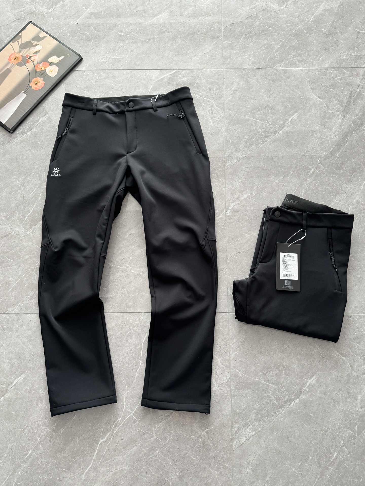 💰235
KAILAS凯石头洛克plus男士保暖防泼抓绒软壳裤
Size: 玄青黑  M-3XL
作为户外爱好者，入手这条凯乐石软壳裤真是秋冬季节的明智之选，加厚加绒的面料摸起来就很有分量，抗静电设计完美解决了秋冬穿脱衣物的火花尴尬，户外活动时再也不用担心静电问题。
面料柔软但足够坚韧，徒步时膝盖和腰部的活动完全不受限制。最贴心的是裤脚设计，收口处理既防风又方便搭配登山靴，细节处可见品牌的用心。特别推荐给需要频繁户外活动的朋友们，保暖实用是真没话说。保暖有型🔥石头洛克plus男士保暖防泼抓绒软壳裤，Yuan单⚠️防风防泼水梭织软壳，内里复合绵密抓绒，无惧风雨还自带发热效果，拒绝老寒腿，外层梭织壳保暖锁温的同时避免臃肿，利落挺括不显厚重✔抗起球不粘毛不缩水，直筒裤型，符合人体工学的3D立裁拼接设计，合身fit修饰腿型不紧绷，温暖舒适又灵活！一粒扣拉链西装腰配腰带装饰，立整有型☑️作为休闲裤来穿灵活舒适，通勤做小西裤干练不拖沓！绝对值得人手一条🥳休闲户外/职场通勤轻松拿捏‼裤管有松量修饰腿型，显瘦藏肉！
户外活动时，徒步时膝盖和腰部的活动完全不受限制。最贴心的是裤脚设计，收口处理既防风又方便搭配登山靴，细节处可见品牌的用心。
☑️3D裤型‼️
整条裤子设计就是简单大气，正面顺色丝光线徽标刺绣点缀，精致简约又有身份辨识度！剪裁很有立体感，利落有型不拖沓！平时搭卫衣、职场通勤配Polo衫、衬衫也没啥违和感～
门襟两处衔接点采用特种机打结固定，腰部内侧缝制加绒布，温暖不反凉，亲肤吸汗。两侧防尘YKK拉链口袋，顺滑耐用不卡顿！印花软胶套结做拉标，装手机安全防丢，加绒内衬保暖且不影响裤型！
膝盖位置后侧拼裁衔接，前侧对应两处立体收褶，上身自带流畅的立体感，臀胯有型不紧绷、不掉裆，不鼓包，提升蹲起时的灵活度～
内里拷边整齐扎实，耐磨耐穿不易撕裂！
脚口带抽绳可调节松紧，有效防风！
☑️双层复合面料‼外高密度梭织软壳，内绵密抓绒，外层防风防泼水，内里锁温保暖御寒，同时双面结构又不会让衣物显得厚重臃肿！
内里100%聚酯，抓绒是整片覆盖式的绵密抓绒，小颗粒绒手感柔软，略偏厚实，穿起来更保暖，提升吸热保暖效率，蓄热抗寒！

凯石头洛克plus 软壳裤
尺码	腰围	臀围	裤长	
M.	84	90	98.5	
L.	88.	98.	100	
XL.	92.	107.	101.5	
2xL.	96.	116.	103	
3xL.	100.	125.	104.5	
推荐体重:
M码:100-120斤
L码:120-140斤XL码:140-160斤
2XL码:160-180斤3XL码:180-200斤
[手工测量存在2-3cm误差属正常现象，
建议尺码仅供参考]