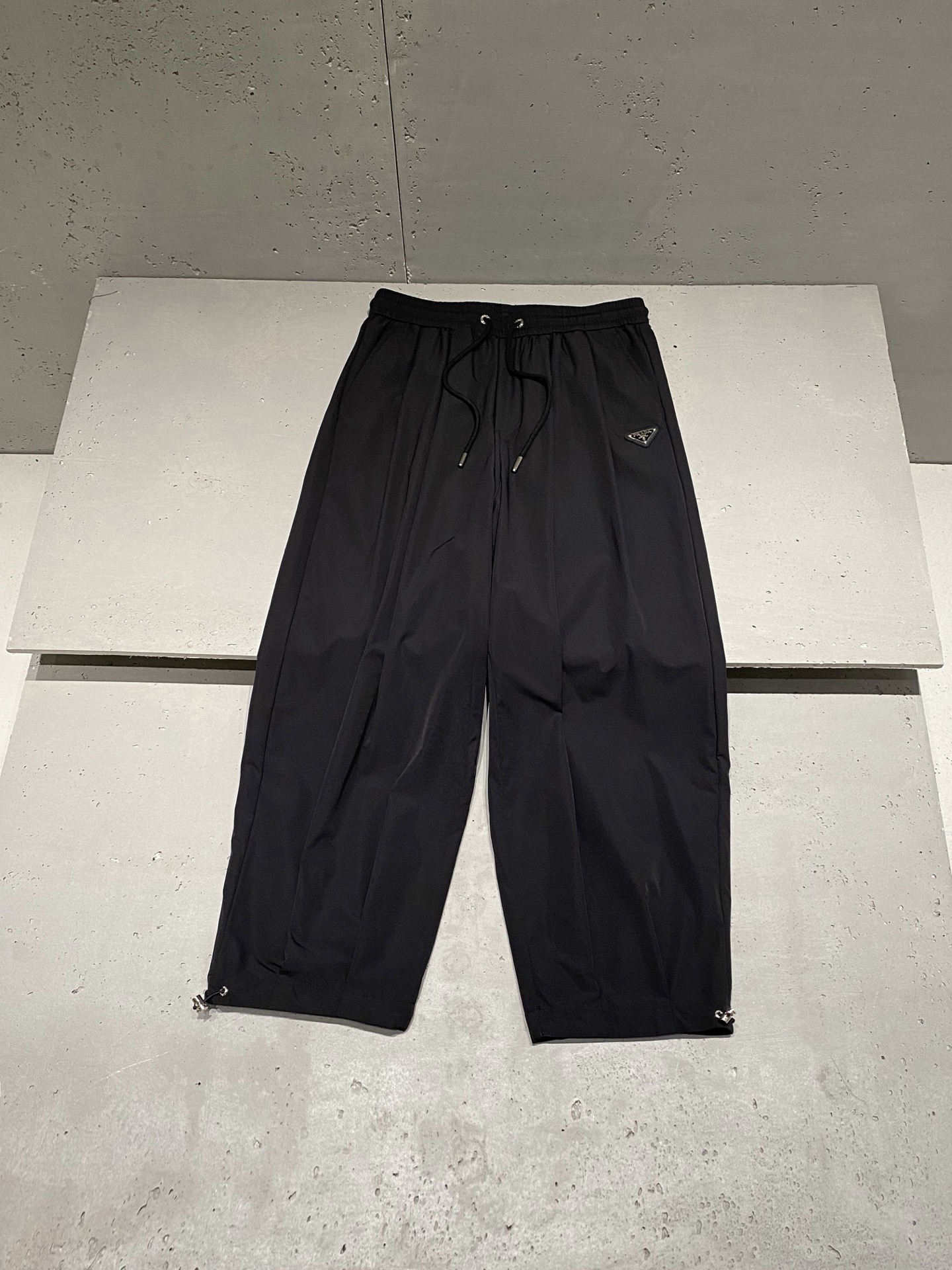 NO:523623,2025 autumn and winter Pr*d* Milano metal badge logo cotton simple loose straight-leg casual pants Light-sensitive cotton woven casual pants woven with a century of craftsmanship to create daily luxury. The natural texture shows the modern and fashionable seasoning... High-density knitted cotton fabric is lightly woven, and the double-layer design makes the trousers present a perfect texture and a bead-like luster. The simple straight loose design is also invincible. The elastic philosophy comes from the elastic waist and adjustable drawstring. The waist and abdomen are wrapped with ergonomic curves, and the metal buckle webbing forms a collision between industrial aesthetics and Italian romantic. Milano metal badge echoes the front and back of the logo label, breaking the silence of a single color. The two-pronged design is unique and ingenious to reflect the beauty of details. Men and women's same style Color: Black Size: XS=29/30 S=31/32 M=33/34  L=36/38 Data XS code: waist circumference 74cm-leg circumference 82cm-crotch position 36cm-pants length 100cm S code: waist circumference 78cm-leg circumference 84cm-crotch position 37cm-pants length 102cm M code: waist circumference 82cm-leg circumference 86cm-crotch position 38cm-pants length 104cm L code: waist circumference 86cm-leg circumference 88cm-crotch position 39cm-pants length 106cm, alexander wang198609092025秋冬Pr*d* Milano金属徽章标识棉质简约宽松直筒休闲裤 光感棉质织韵休闲长裤,以百年工艺织就日常奢华.自然肌理展现现代时尚的调味剂… 高密针织棉质面料轻纺织造而成,双层设计让裤装呈现完美质感,流淌着珠般光泽. 简约直筒宽松设计感也是无敌.松紧哲学来自弹力腰间与可调节抽绳.以人体工学曲线包裹腰腹,金属扣头织带形成工业美学与意式浪漫的碰撞. Milano金属徽章与标识标签前后呼应,划破单一色系的寂静.双管齐下的设计别具匠心体现细节美感. 男女同款 颜色:黑色 尺码:XS=29/30 S=31/32 M=33/34 L=36/38 数据 XS码:腰围74cm-腿围82cm-裆位36cm-裤长100cm S码:腰围78cm-腿围84cm-裆位37cm-裤长102cm M码:腰围82cm-腿围86cm-裆位38cm-裤长104cm L码:腰围86cm-腿围88cm-裆位39cm-裤长106cm,,alexander wang,Men's clothing