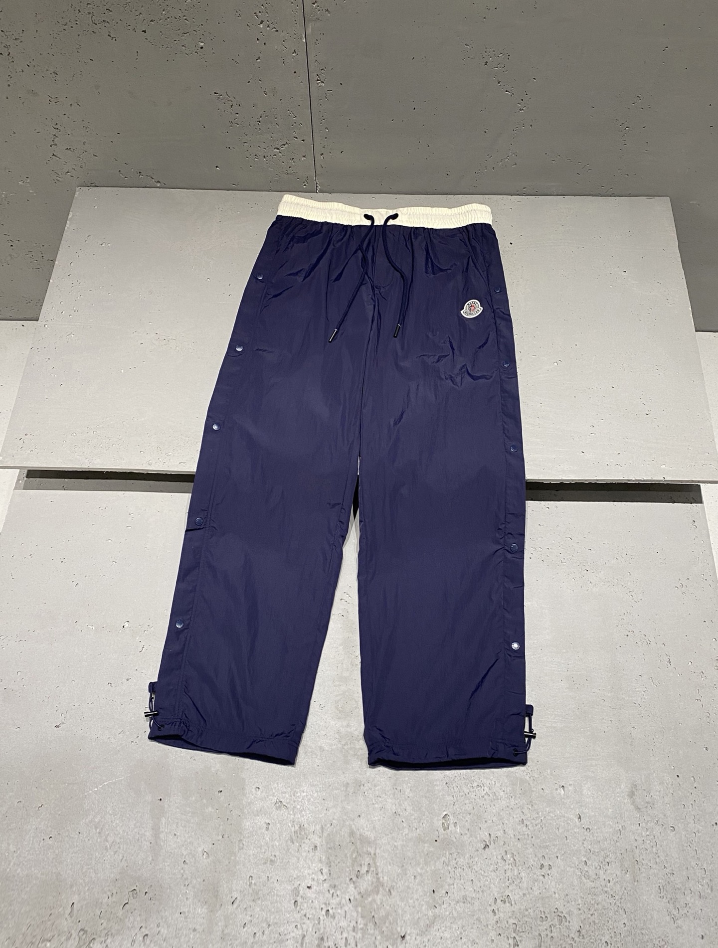 NO:530067,Autumn and winter Mo*cler joint logo badge sports and casual trousers. Fashionable matching, the cutting design conforms to the trendy and fashionable charm. The embroidered badge logo brings new ideas for sports and leisure in the new era. Customer-supplied polyester nylon nylon fabric, with a different feel and drape between ordinary nylon surfaces, and has breathable and soft characteristics. The contrasting color between waist + side snap buttons of the trousers highlights the unique charm of modern cutting technology and the brand, with uniform and bright colors, comfortable and breathable texture to interpret the retro sports style. Men and women's same style Color: Navy blue Size: XS=29/30 S=31/32 M=33/34 L=36/38 Data XS: waist circumference 76cm-leg circumference 34cm-crotch position 31cm-trouser length 101cm  S: Waist circumference 80cm-leg circumference 35cm-crotch position 32cm-trouser length 103cm M: Waist circumference 84cm-leg circumference 36cm-crotch position 33cm-trouser length 105cm L: Waist circumference 88cm-leg circumference 37cm-crotch position 34cm-trouser length 107cm, alexander wang19860909秋冬Mo*cler 联名款标识徽章运动休闲长裤 时尚搭配美品,裁剪设计符合潮流时尚韵味,刺绣徽章标识为新时代运动休闲带来新意. 客供聚酯锦纶尼龙面料,手感及垂坠感区别普通尼龙面,拥有透气柔软的特性. 腰间撞色拼接＋裤子侧边按扣设计彰显现代裁剪工艺及品牌的独特魅力,色泽均匀艳丽,质感舒适透气演绎复古运动风范. 男女同款 颜色:藏蓝色 尺码:XS=29/30 S=31/32 M=33/34 L=36/38 数据 XS码:腰围76cm-腿围34cm-裆位31cm-裤长101cm S码:腰围80cm-腿围35cm-裆位32cm-裤长103cm M码:腰围84cm-腿围36cm-裆位33cm-裤长105cm L码:腰围88cm-腿围37cm-裆位34cm-裤长107cm,,alexander wang,Men's clothing