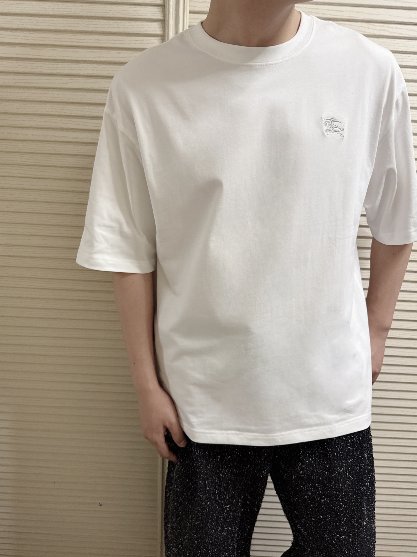 NO:856006,2026 Spring and Summer Bur*e*ry Classic War Horse Embroidered Logo Short-Sleeved T-Shirt. The classic style cutting and slit design are combined to form a simple and fashionable style carrier. The exquisite craftsmanship is unparalleled. The high-quality island spandex fiber cotton blended fabric is produced using advanced knitting micro-density equipment to ensure the cutting shape and characteristics. The ready-made garment is breathable and comfortable, soft and delicate to the touch, and has trendy and fashionable charm.  The classic shape of the war horse badge increases the visual enjoyment of the eye. It is decorated with gold and silver silk fiber needle point embroidery, which is saturated and lifelike. Same style for men and women. Color: white/black Size: XS/S/M/L Data  M code: Bust 118cm - Shoulder width 56cm - Clothes length 74cm - Sleeve length 26cm L code: Bust 122cm - Shoulder width 57cm - Clothes length 75cm - Sleeve length 27cm, burberry, T-shirt, tees, t-shirt,198609092026春夏Bur*e*ry 经典战马刺绣标识短袖T恤 经典风格裁剪及切缝设计相结合形成简约时尚风格的承载体,精湛的工艺无与伦比. 优质海岛氨纶纤维棉质混纺面料,运用先进的针织微密型器械制作保证了裁剪造型和特色,成衣透气舒适,手感柔软细腻兼具潮流时尚魅力. 经典造型战马徽章增加了眼球的视觉享受.运用金银色丝线纤维针点刺绣装饰,饱和凛然,栩栩如生. 男女同款 颜色:白色/黑色 尺码:XS/S/M/L 数据 XS码:胸围110cm-肩宽54cm-衣长72cm-袖长24cm S码:胸围114cm-肩宽55cm-衣长73cm-袖长25cm M码:胸围118cm-肩宽56cm-衣长74cm-袖长26cm L码:胸围122cm-肩宽57cm-衣长75cm-袖长27cm,,burberry,T-shirt,tees，t-shirt,,Men's clothing