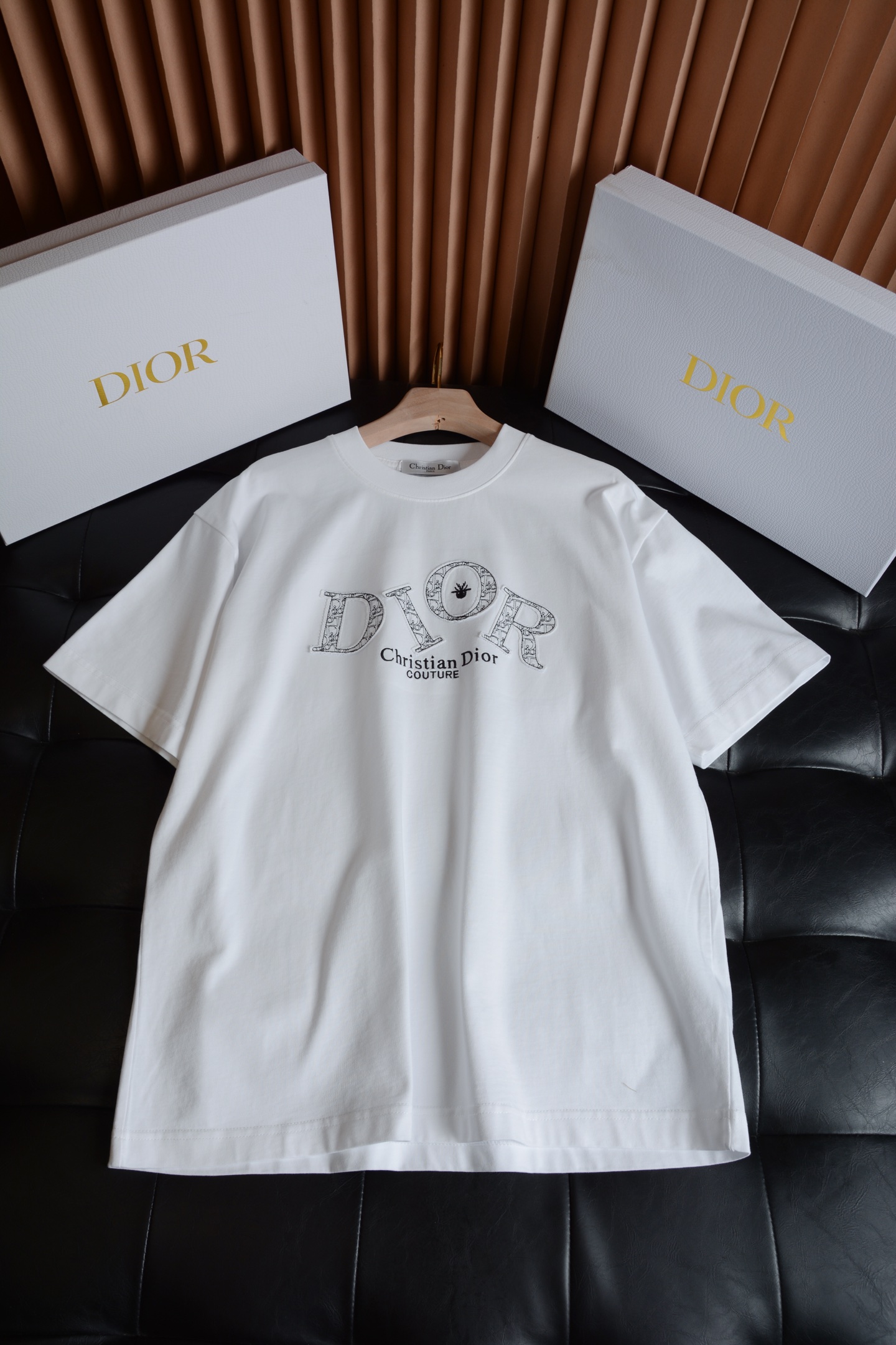 NO:786963,Embroidery details · Brand soul  The embroidered LOGO on the chest is the core highlight of the entire T-shirt, giving the brand's classic elements a high-end texture. The embroidered letters 'DIOR' are embroidered with the brand's classic Oblique presbyopic texture. The edges are neatly and delicately routed, and the embroidery is full and three-dimensional. It has an obvious texture to the touch, but does not irritate the skin at all.  , the black/white background color forms a soft contrast with the embroidery tone, which is low-key and recognizable. The little bee embroidery in the center of the letter 'O' is the iconic brand symbol of DIOR. The workmanship is exquisite and compact, echoing the overall old flower embroidery, adding a sense of smart detail.  The words 'Dior COUTURE' are exquisitely printed in the same color, and the fonts are clear and neat, without destroying the overall sense of simplicity. Collar label details The brand woven label on the inside of the neckline is neatly made, with a clear brand logo, clean lines, and an authentic level of detail and texture. Fabric texture · Skin-friendly and stiff.  The entire T-shirt is made of high-count heavyweight pure cotton fabric, which combines comfortable wearing feeling with firmness. The fabric is of sufficient weight, soft and delicate to the touch, but has a certain stiffness. The upper body will not collapse against the skin, and can well modify the body shape. At the same time, it has excellent breathability, and will not be stuffy and sticky when worn in summer. The fabric has been specially pre-shrunk, so it will not be easily deformed and shrunk by daily machine washing.  It can still maintain a flat shape after the first wear, is not easy to pill, and has a durable texture that can be worn for a long time. The color fastness of the fabric is excellent, the black and white background is clean and even, without noise and color difference, the texture is high-end, the upper body has a soft matte luster, and there is no reflective feeling of cheap T-shirts., Dior-clothing, dior, dior, tees, t-shirt,19860909刺绣细节 · 品牌灵魂 胸前的刺绣LOGO是整件T恤的核心亮点,把品牌的经典元素玩出了高级质感.字母刺绣“DIOR”字母采用品牌经典的Oblique老花纹理刺绣,边缘走线工整细腻,刺绣饱满立体,摸上去有明显的肌理感,却完全不会硌肤,黑/白双色的底色与刺绣色调形成柔和对比,低调又有辨识度.点睛设计字母“O”中心的小蜜蜂刺绣,是DIOR标志性的品牌符号,做工精致小巧,和整体的老花刺绣呼应,增添了几分灵动的细节感,下方的“Christian Dior COUTURE”字样采用同色系精致印花,字体清晰利落,不破坏整体的简约感.领标细节领口内侧的品牌织标做工规整,带有清晰的品牌标识,走线干净,是正品级别的细节质感. 面料质感 · 亲肤与挺括兼具 整件T恤采用高支重磅纯棉面料打造,兼顾了舒适穿着感与版型挺括度.面料克重充足,摸上去手感柔软细腻,却自带一定的挺括感,上身不会软塌贴肤,能很好地修饰身形,同时透气性优秀,夏天穿着也不会闷热黏腻.面料经过特殊预缩处理,日常机洗不易变形缩水,多次穿着依然能保持平整的版型,不易起球,是能穿很久的耐用质感.面料的色牢度表现优秀,黑白两色的底色干净均匀,没有杂色和色差,质感高级,上身自带柔和的哑光光泽,完全没有廉价T恤的反光感.,迪奥-服装,dior,dior,tees，t-shirt,,Women's clothing