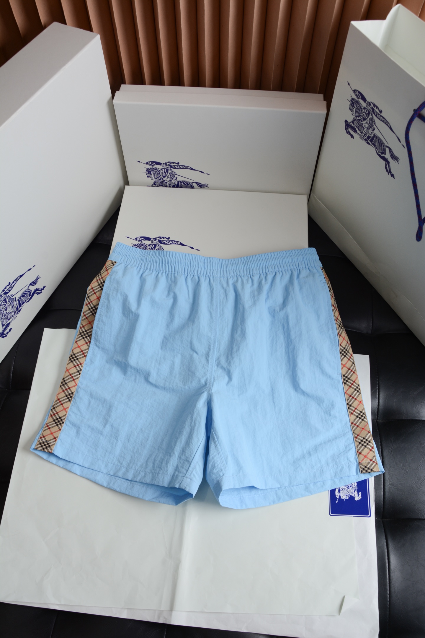 NO:786899,Blue hardware details have a warm texture and conceal brand recognition. The waistband adopts custom-made matte texture drawstring hardware, and the surface has been treated with anti-oxidation plating. The color is fine and non-glaring, harmoniously echoing the color of the pants, low-key and not exaggerated. The drawstring adjustment is smooth and not stuck, and there is no cheap loose feeling. The side pocket zipper uses brand-specific hardware, with precise bite and no noise when pulling. The details hide the exclusive luxury brand texture, which is restrained and high-end.  Fabric technology, light texture, breathable and quick-drying  The whole piece is made of brand-customized high-density polyester fiber woven fabric, which presents a delicate and natural texture on a solid color base. The side straps are woven into Burberry's iconic Vintage plaid, with neat alignment and bright colors.  The transition is soft, showing the British style under the light and shadow. The fabric is light and skin-friendly, with inherent stiffness. The upper body is not soft or clinging to the flesh. It has both breathability and drape. It is not stuffy and sweaty when worn in summer. It is not easy to deform or pill after being washed for a long time, and the texture is online.  The cut is neat and loose, not flattering on the body shape  Adopting a classic slightly loose straight fit, the trousers are neat and not draggy. The waistband is designed with elasticity, which can adapt to a wider range of waistlines without being too picky about the figure. The trousers are at a prime position above the knee, and the side plaid ribbon extends from the waistband to the trousers, visually modifying the proportions of the legs. The overall cut is clean and neat, and the upper body can modify the body shape without appearing restrictive. Whether it is paired with a T-shirt, a sweatshirt or a shirt, it can create a relaxed and high-end atmosphere.  These side plaid casual shorts are an excellent choice to bring Burberry's classics into daily life. They are low-key and unobtrusive, but full of texture details. They can easily be used as versatile textures in men's wardrobes. Burberry - Clothing, burberry, hoodie, sweatshirts, shorts, shirts, tees, t-shirt, gold,19860909蓝色 五金细节温润质感,暗藏品牌辨识度 腰头采用定制的哑光质感抽绳五金头,表面经过防氧化电镀处理,色泽细腻不刺眼,与裤身色调和谐呼应,低调不浮夸.抽绳调节顺滑不卡顿,无廉价松动感.侧袋拉链采用品牌专用五金件,咬合精密,拉动时无杂音,细节里藏着专属的奢牌质感,内敛又高级. 面料工艺轻薄肌理,透气速干 整件采用品牌定制的高密聚酯纤维梭织面料,在纯色基底上呈现细腻自然的肌理感,侧边饰带织入Burberry标志性Vintage格纹,格纹对位工整,色彩过渡柔和,在光影下尽显英伦格调.面料触感轻薄亲肤,自带挺括度,上身不软塌、不贴肉,兼具透气性与垂坠感,夏天穿也不闷汗,久洗不易变形、起球,质感在线. 版型剪裁利落松弛,不挑身形 采用经典的微宽松直筒版型,裤型利落不拖沓,腰头为弹力松紧设计,对腰围的适配范围更广,不挑身材；裤长及膝上黄金位置,侧边格纹饰带从腰头延伸至裤脚,视觉上修饰腿型比例.整体剪裁干净利落,上身既能修饰身形,又不会显得拘谨,无论是搭配T恤、卫衣还是衬衫,都能穿出松弛又高级的氛围感. 这件侧边格纹休闲短裤,是把Burberry的经典穿进日常的绝佳选择,低调不张扬,却处处都是质感细节,轻松拿捏男士衣橱里的百搭质感担当.,博柏利-服装,burberry,hoodie,sweatshirts,shorts,shirts,tees，t-shirt,gold,,Women's clothing