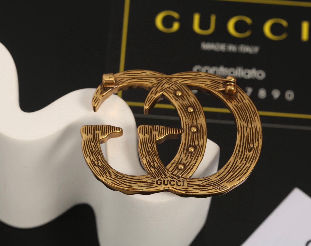 Gucci双G古驰胸针作为品牌的标志性元素运用品牌首字母以别致的方式呈现金色效果金属标识与白色玻璃珍珠边