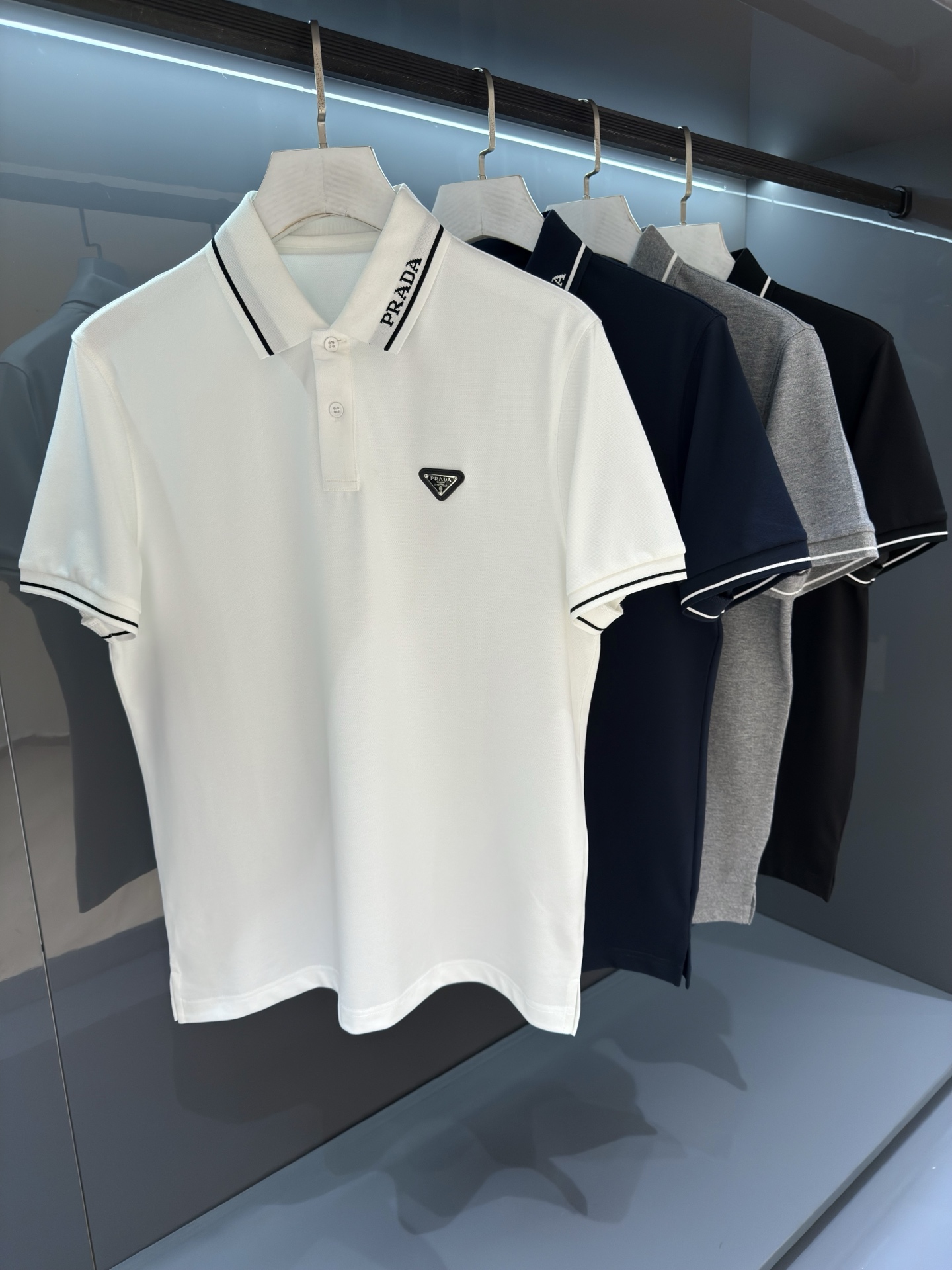 NO:833955,Pr*da 26SS new spring and summer men's business fashion casual polo shirt lapel short-sleeved T-shirt  Classic letter embroidery design decoration, suitable for casual and business use, fashionable with the times, always eye-catching with a unique attitude. The Piquet air hole piqué cotton fabric provided by the customer can be called 'fabric that breathes', and the technical knitted quilting design makes the hand feel extremely smooth and delicate without any roughness, making it more comfortable and breathable. Clothes  Both sides of the sleeves are decorated with 2026's characteristic detailed striped inlays, and the precisely controlled knitted texture interprets the most classic and luxurious P style charm. The classic straight-cut double-needle hem and rib knitted cuffs are neatly created to create a fashionable and rigorous luxury atmosphere. The texture is thick and full, and the luster is brilliant. Every detail is a reflection of luxury and temptation.  Color: black/white/grey/navy size M/L/XL/2XL/3XL M shoulder width 43 chest 102 length 68 sleeve length 21, T-shirt, tees, t-shirt,19860909Pr*da 26SS春夏新品 男士商务时尚休闲polo衫翻领短袖T恤 经典的字母刺绣设计装饰、休闲商务通吃,时髦感与时俱来,时刻以别样的姿态引人注目.客供Piquet气孔珠地棉面料,堪称“会呼吸的面料”,工艺针织绗缝设计让手感极为顺滑细腻,无任何粗糙感,着身更为舒爽透气.衣袖两侧饰有2026的特色细节条纹嵌织,数械精控的针织质感演绎最经典奢华的P家造型魅力.经典的直裁双针下摆及罗纹针织袖口工整无比营造出时尚严谨的奢华气息,质感厚实饱满,光泽出彩.每一处细节都是奢感诱惑的体现. 颜色:黑色/白色/灰色/藏青色 尺码M/L/XL/2XL/3XL M肩宽43胸围102衣长68袖长21,,T-shirt,tees，t-shirt,,Men's clothing