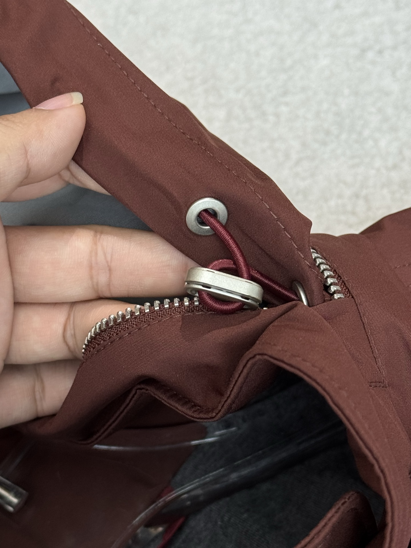 带有可藏式连帽设计，帽子内部衬里颜色与外套内里相呼应，满足不同穿搭需求和天气变化，增加了外套的实用性和穿