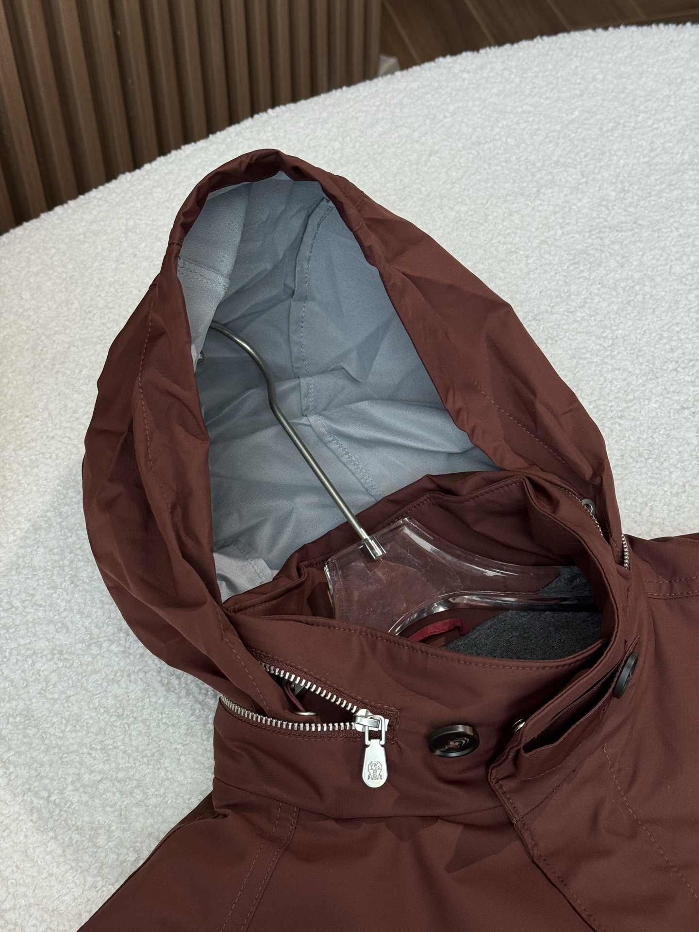 带有可藏式连帽设计，帽子内部衬里颜色与外套内里相呼应，满足不同穿搭需求和天气变化，增加了外套的实用性和穿