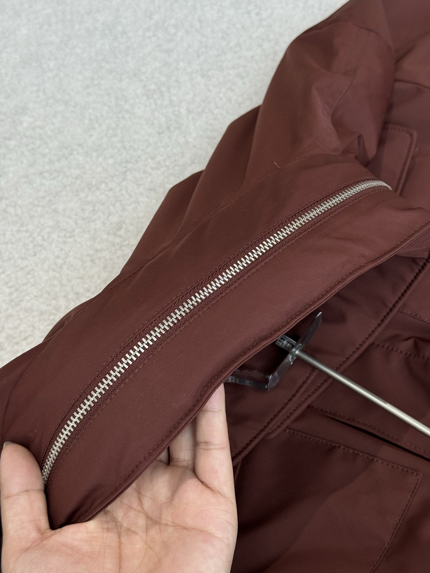 带有可藏式连帽设计，帽子内部衬里颜色与外套内里相呼应，满足不同穿搭需求和天气变化，增加了外套的实用性和穿