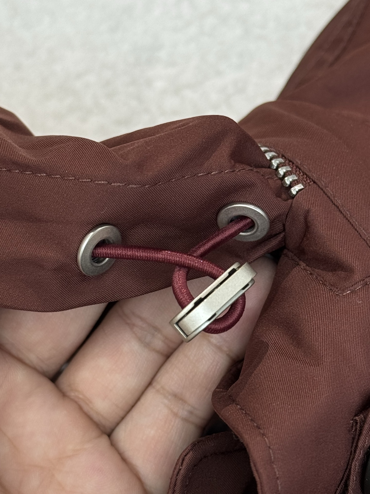 带有可藏式连帽设计，帽子内部衬里颜色与外套内里相呼应，满足不同穿搭需求和天气变化，增加了外套的实用性和穿