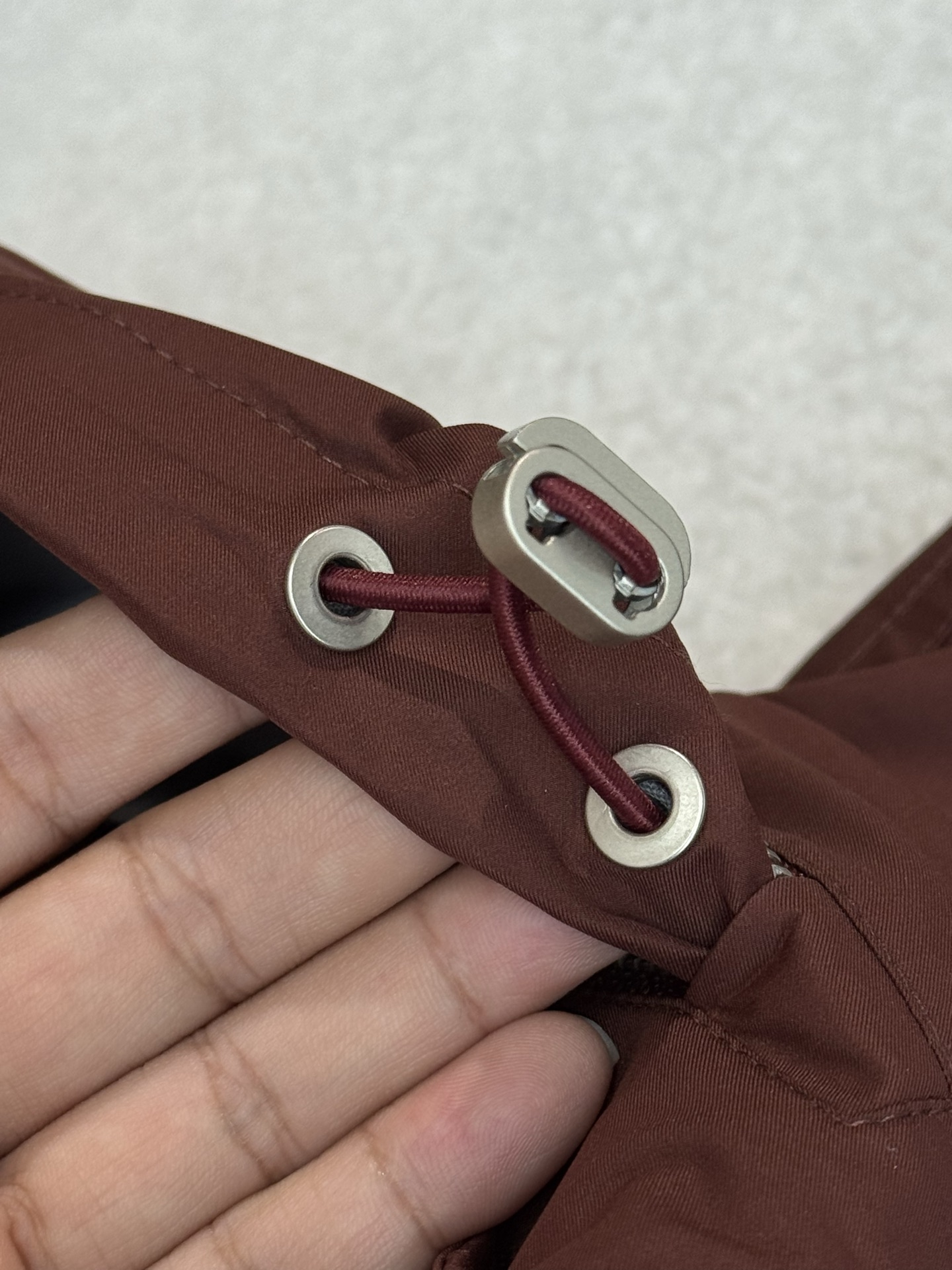 带有可藏式连帽设计，帽子内部衬里颜色与外套内里相呼应，满足不同穿搭需求和天气变化，增加了外套的实用性和穿