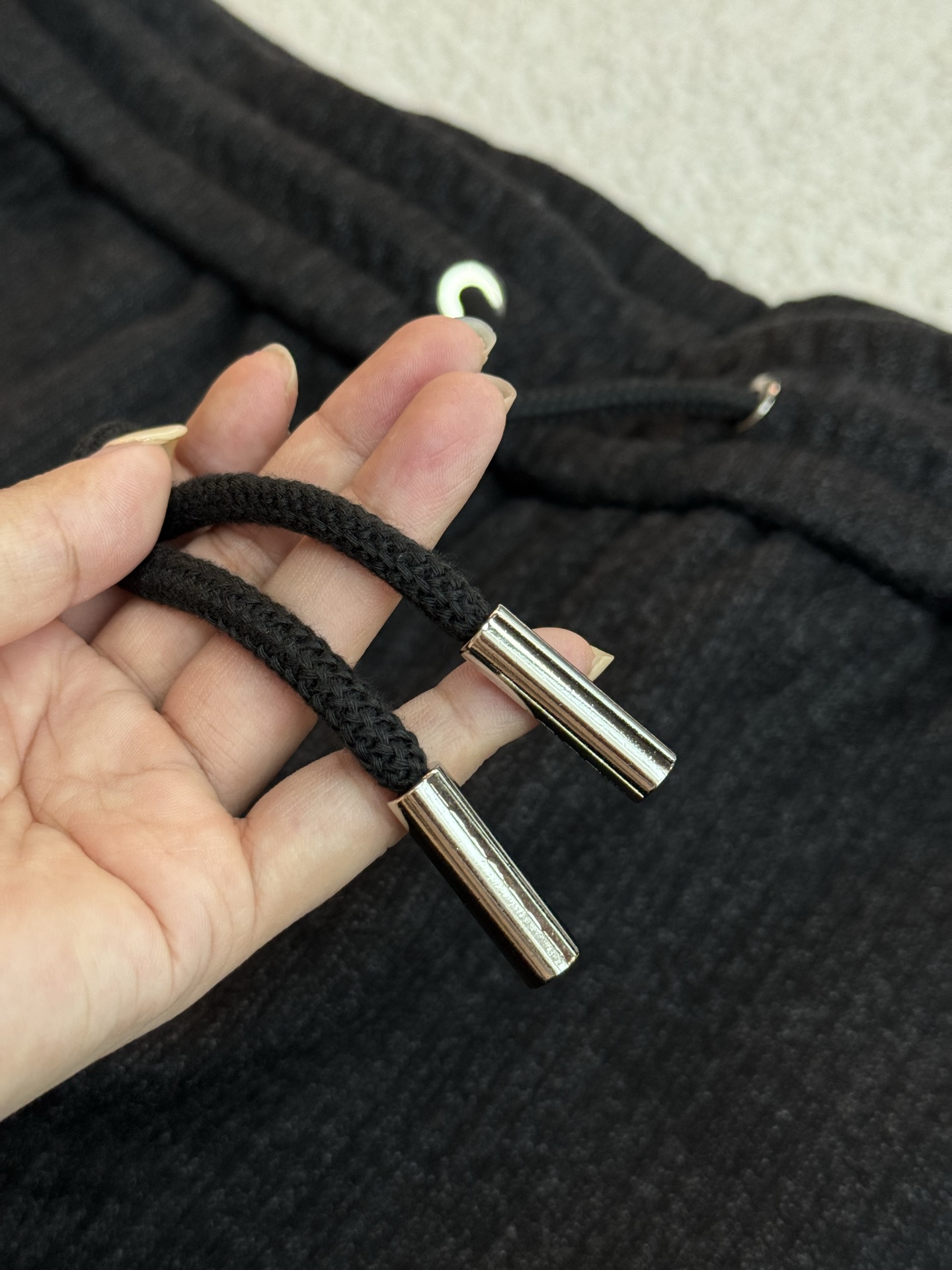 采用抽绳设计，抽绳为黑色编织绳，两端搭配金属质感的圆柱型绳头