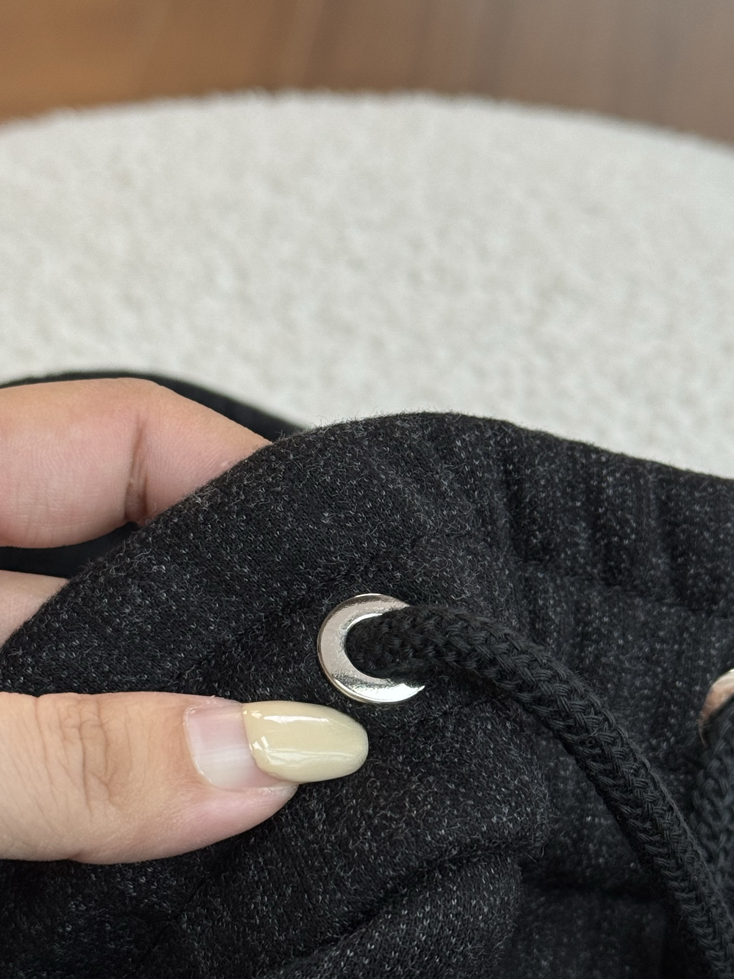 采用抽绳设计，抽绳为黑色编织绳，两端搭配金属质感的圆柱型绳头